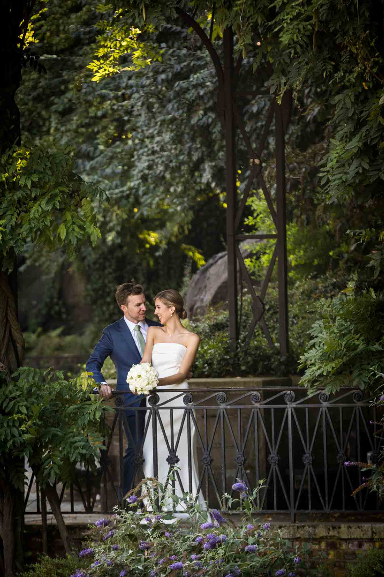 Couple standing by railing along Wisteria Terrace during a Conservatory Garden wedding in Central Park
