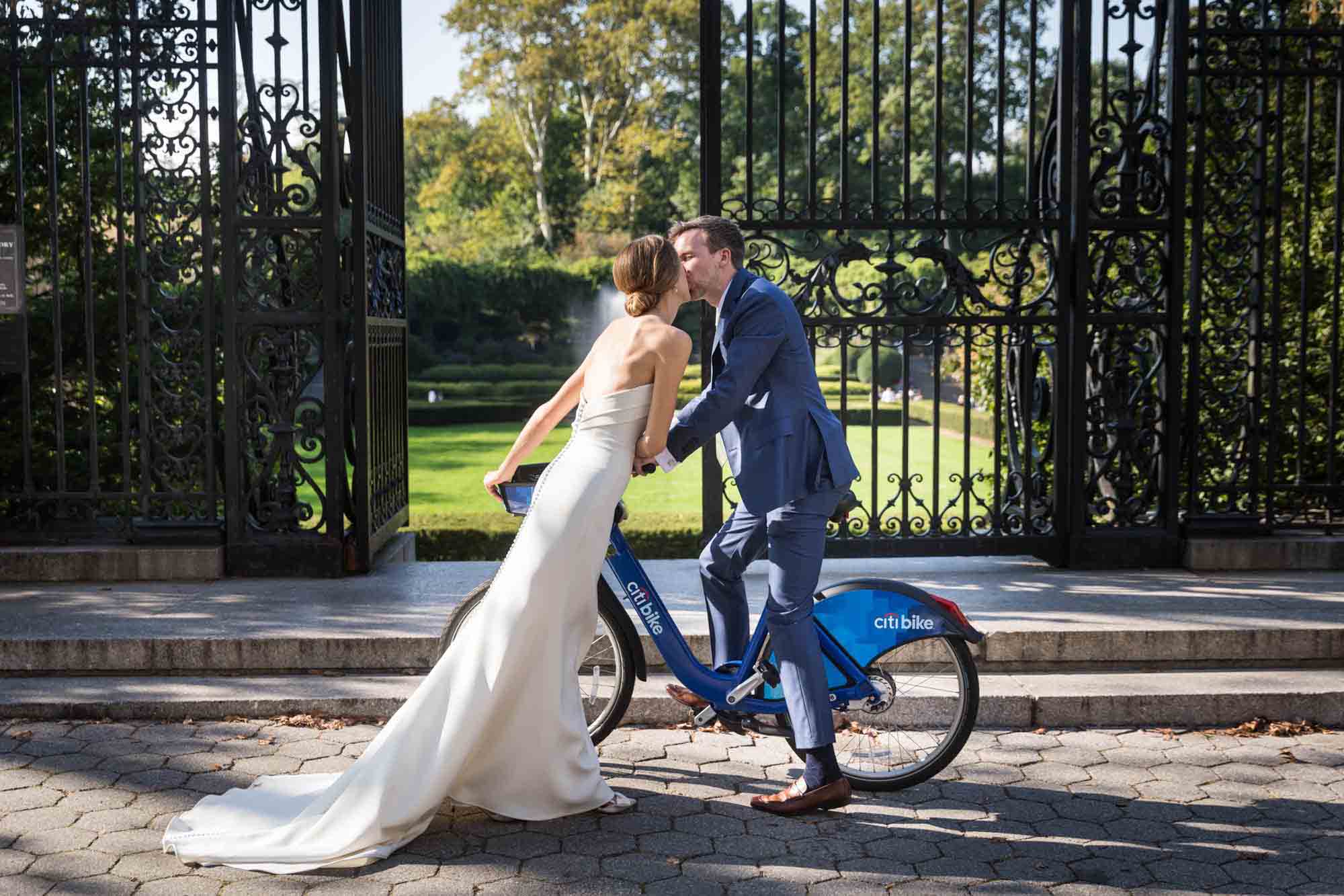 Conservatory Garden wedding photos of bride kissing groom on back of Citi Bike