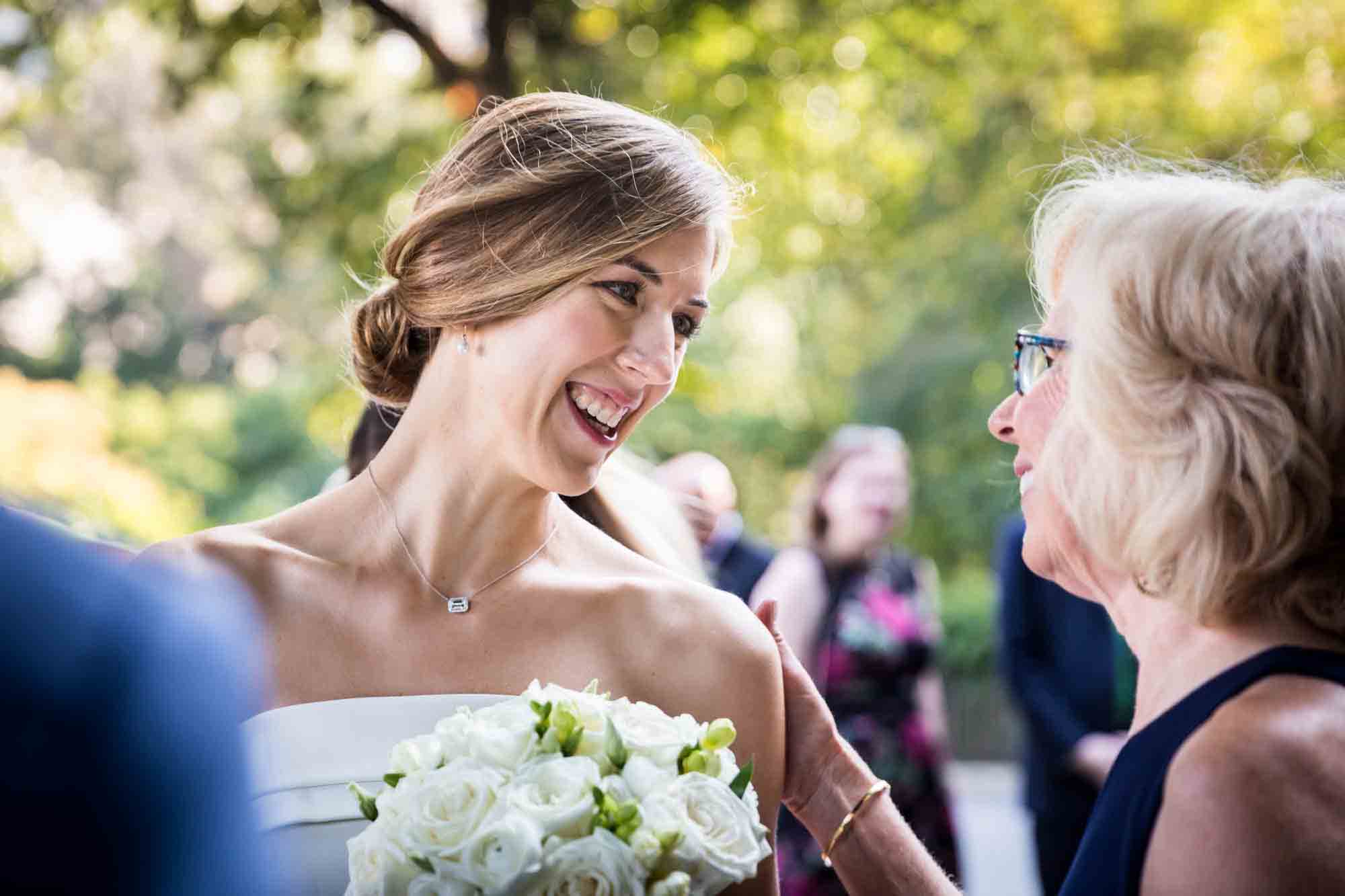 Bride holding bouquet and laughing with older guest during a Conservatory Garden wedding in Central Park