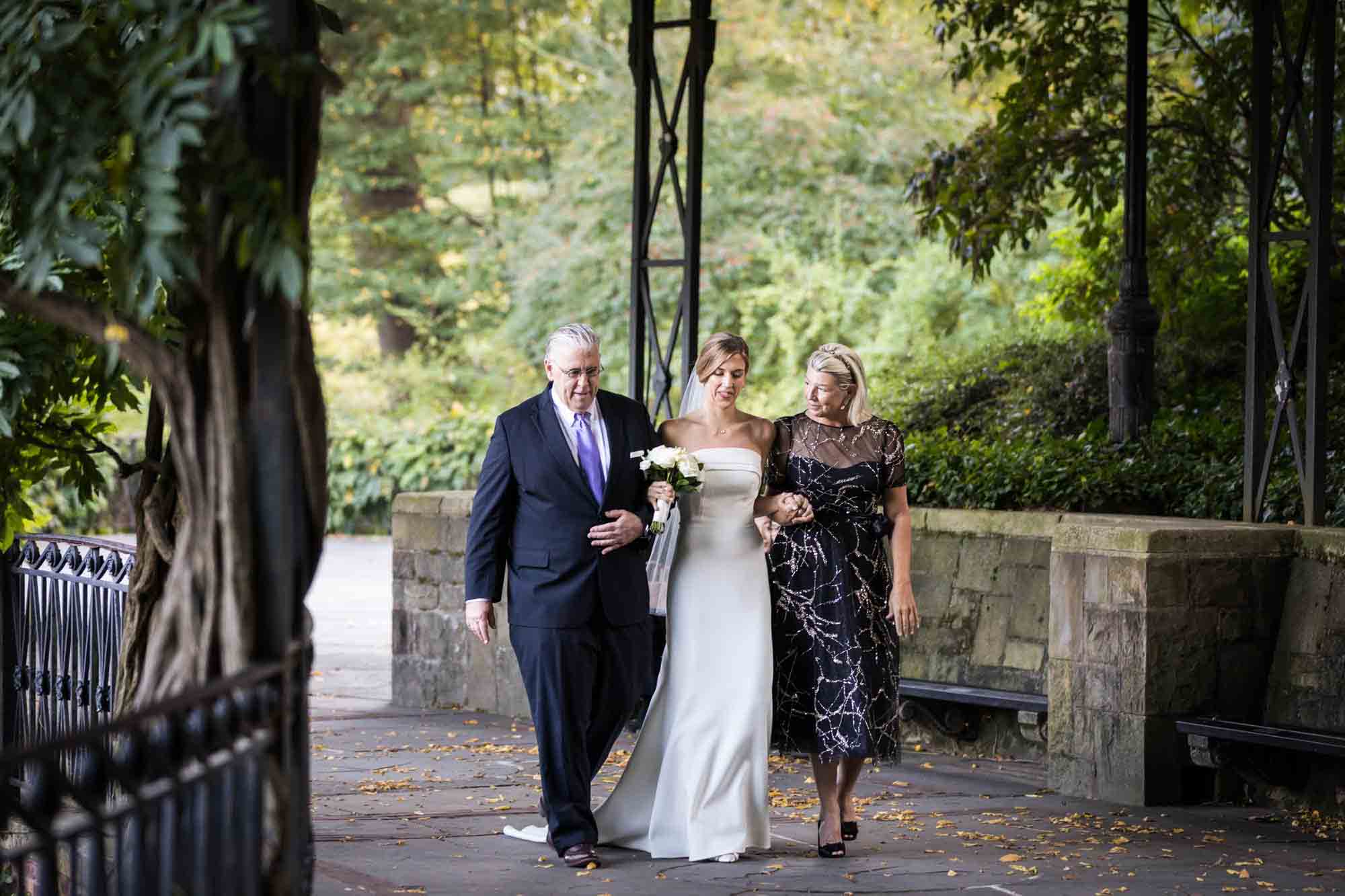 Bride and father walking up aisle on Wisteria Terrace during a Conservatory Garden wedding in Central Park