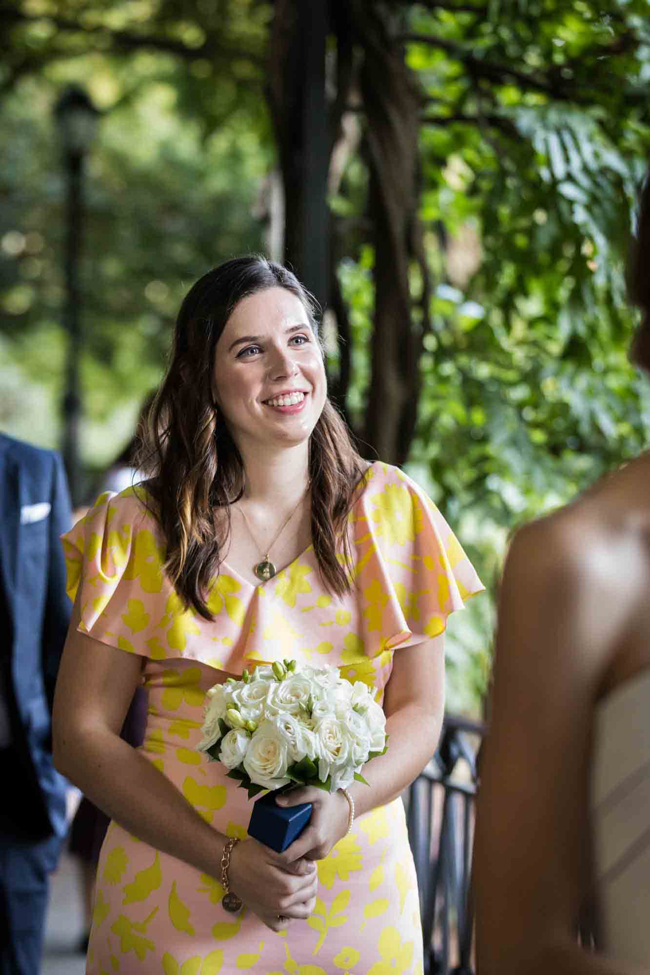 Maid of honor wearing yellow dress and holding bouquet during a Conservatory Garden wedding in Central Park