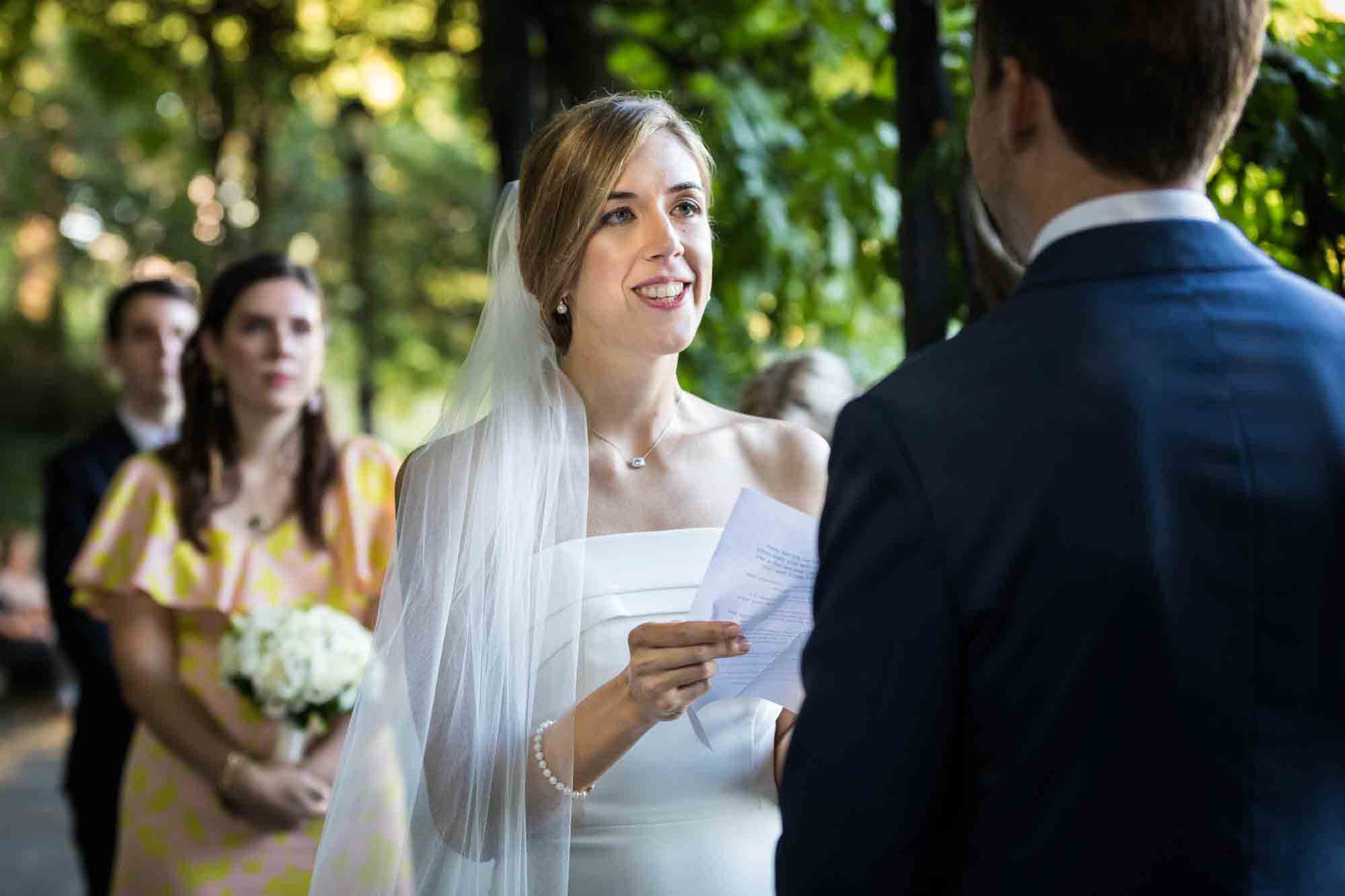 Bride holding paper and saying vows to groom during a Conservatory Garden wedding in Central Park