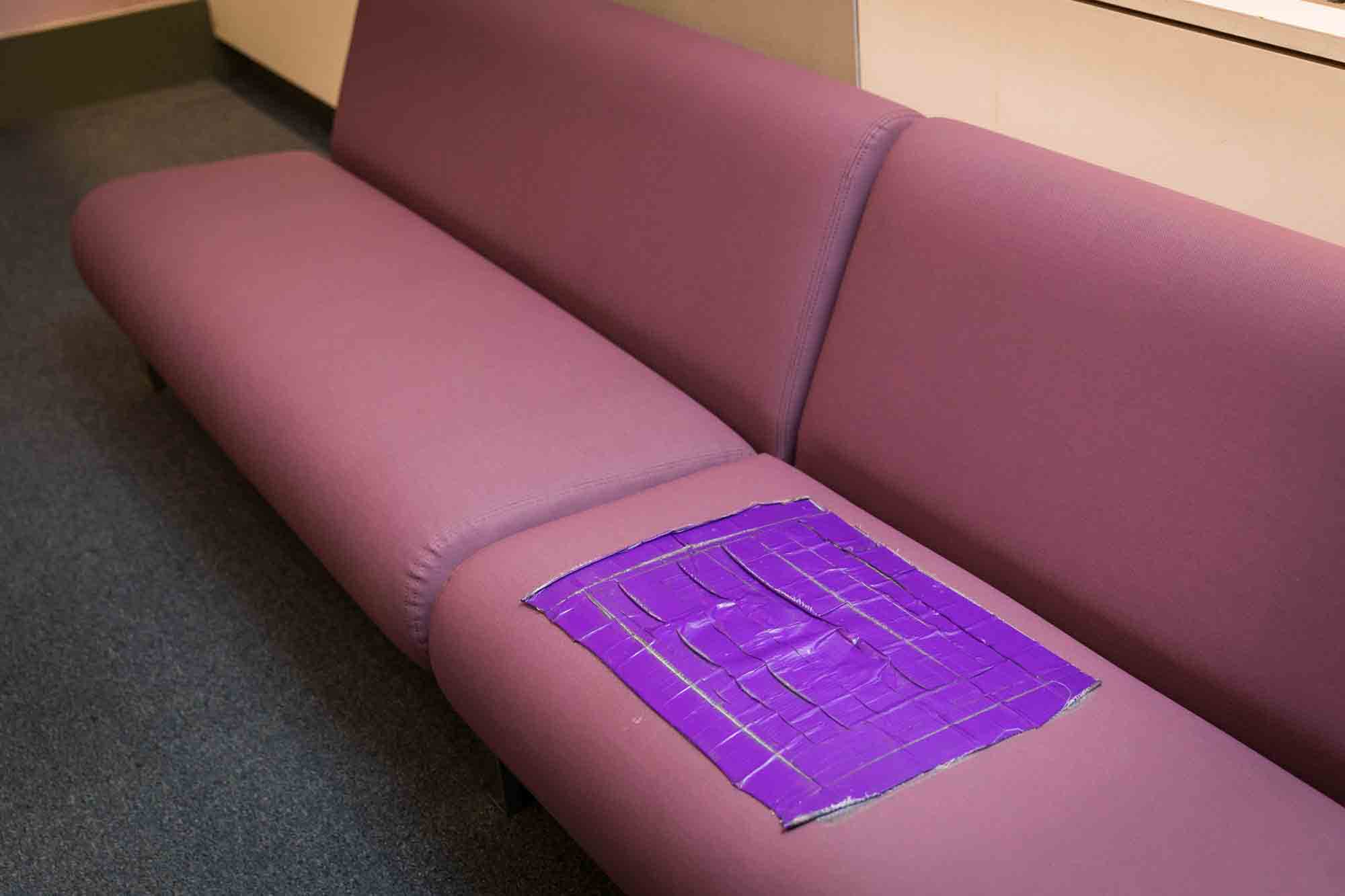 Purple couch with large square of purple duct tape covering hole for an article on how to elope in NYC