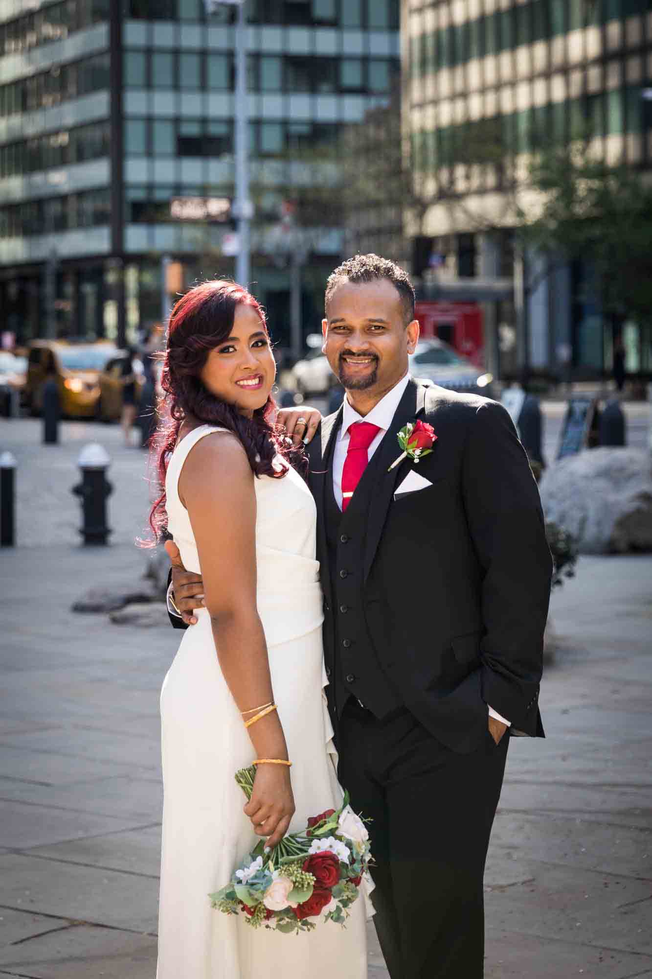 Bride and groom standing on NYC sidewalk looking into camera