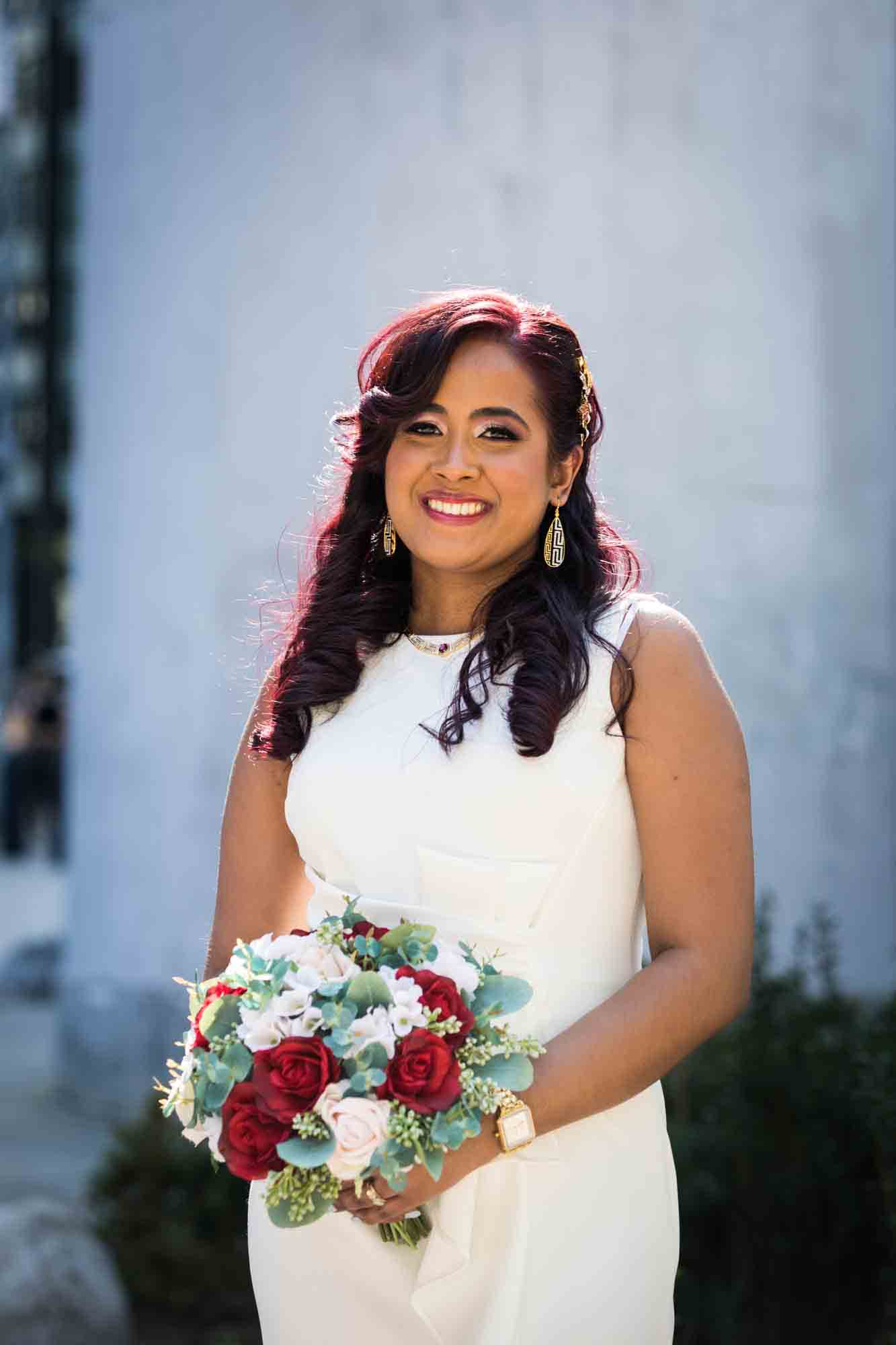 Bride with long brown hair holding flower bouquet on NYC sidewalk