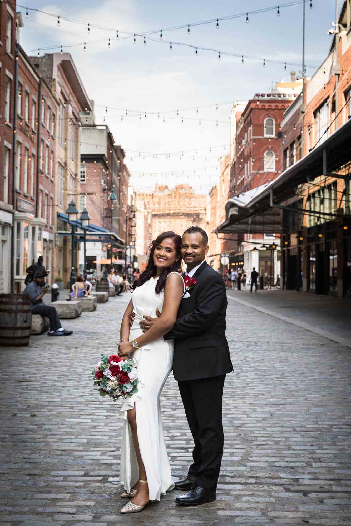 Bride and groom hugging on cobblestone street in South Street Seaport