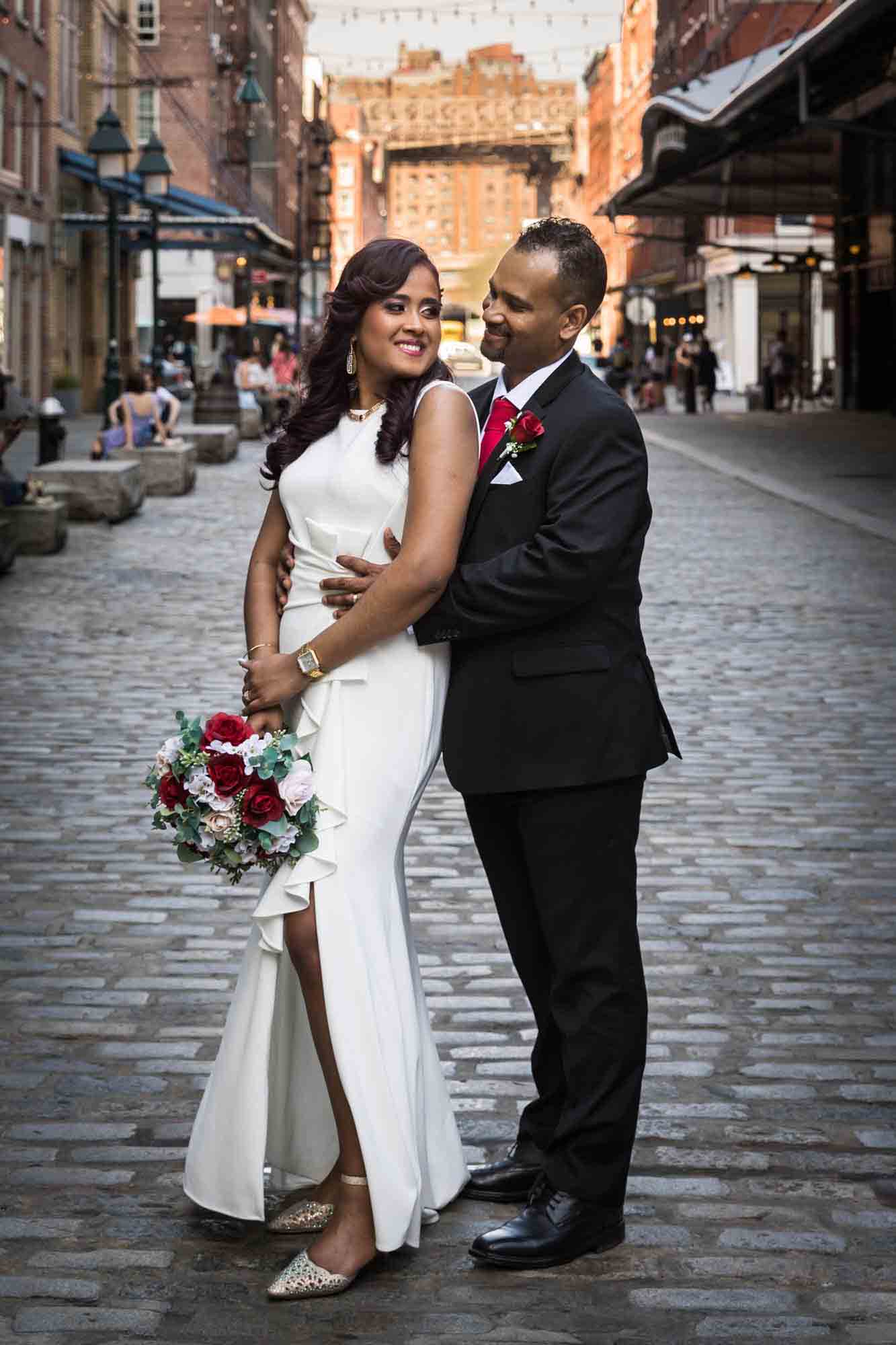 Bride and groom hugging on cobblestone street in South Street Seaport