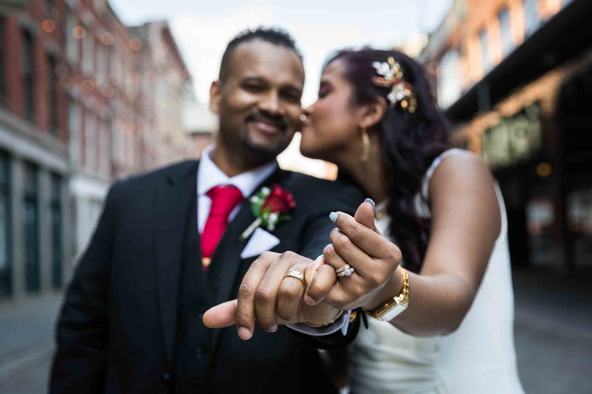 Bride and groom with hands stretched out to camera showing wedding rings