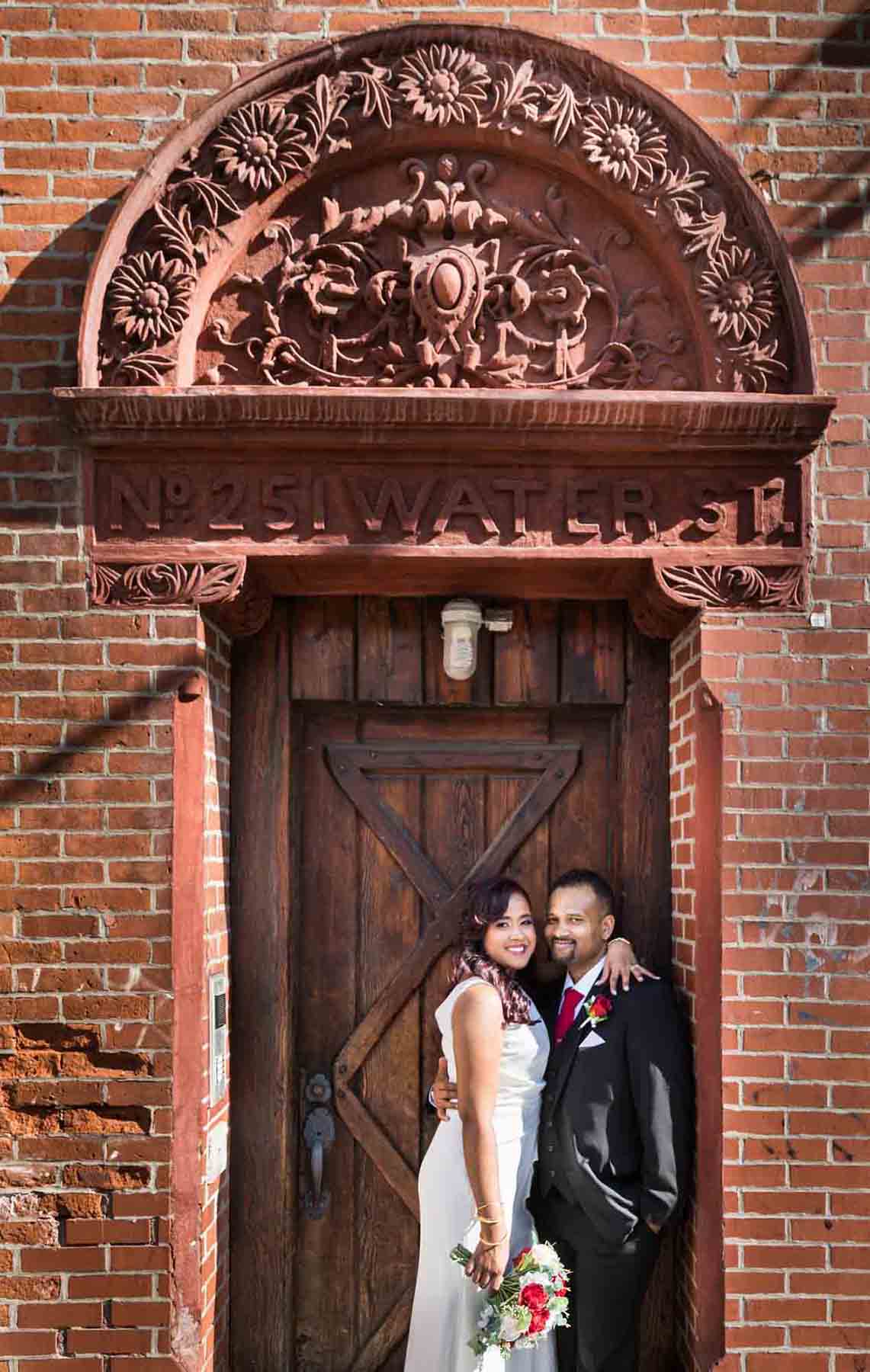 Bride and groom hugging in doorway of brick building