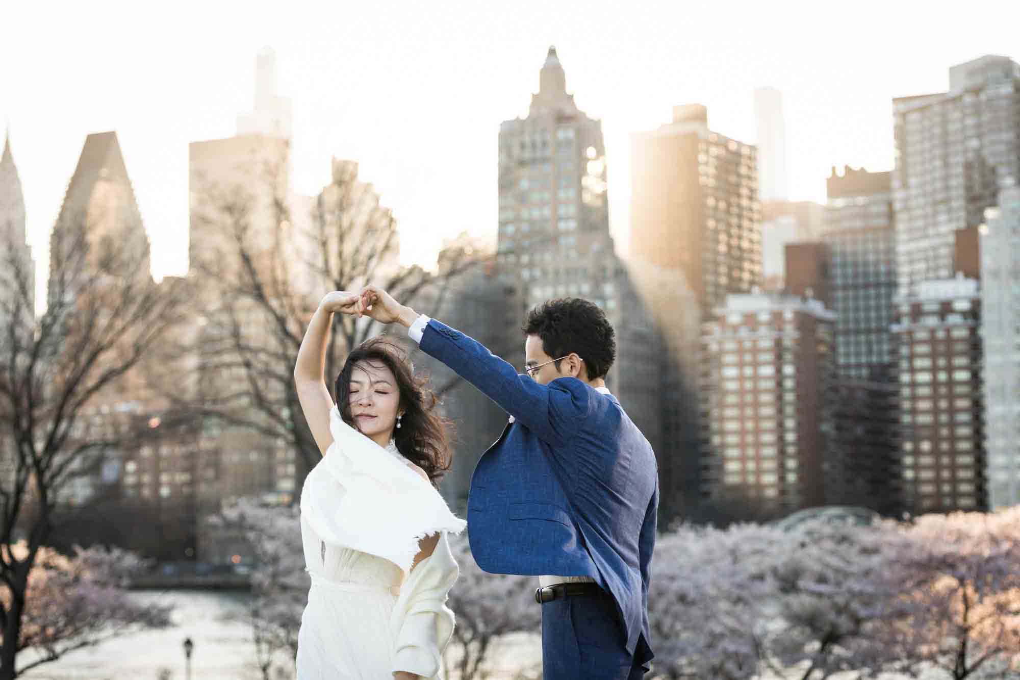 Couple dancing in front of NYC skyline at sunset during a Roosevelt Island engagement photo shoot