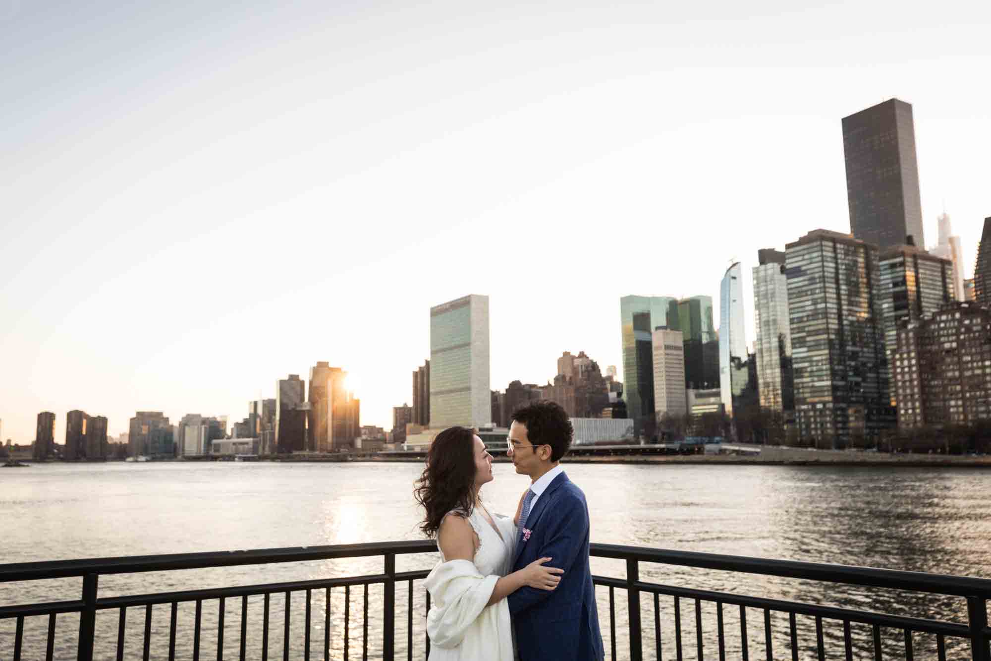 Roosevelt Island engagement photos of couple in front of railing in front of NYC skyline