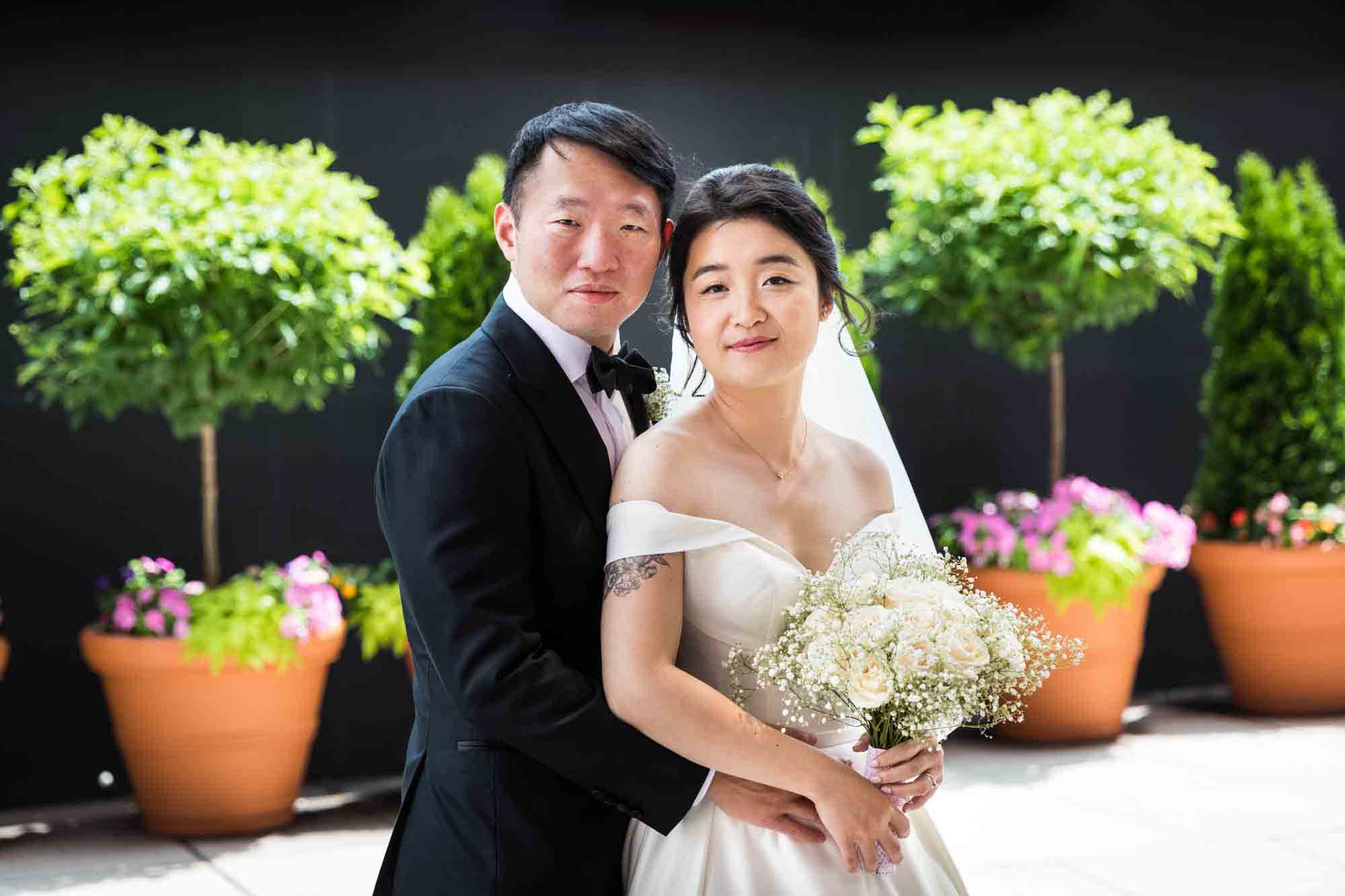 Bride and groom posed in front of potted bushes at a Sheraton LaGuardia East Hotel wedding