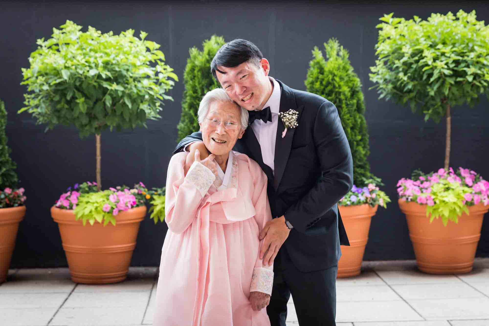 Groom hugging grandmother wearing pink hanbok at a Sheraton LaGuardia East Hotel wedding