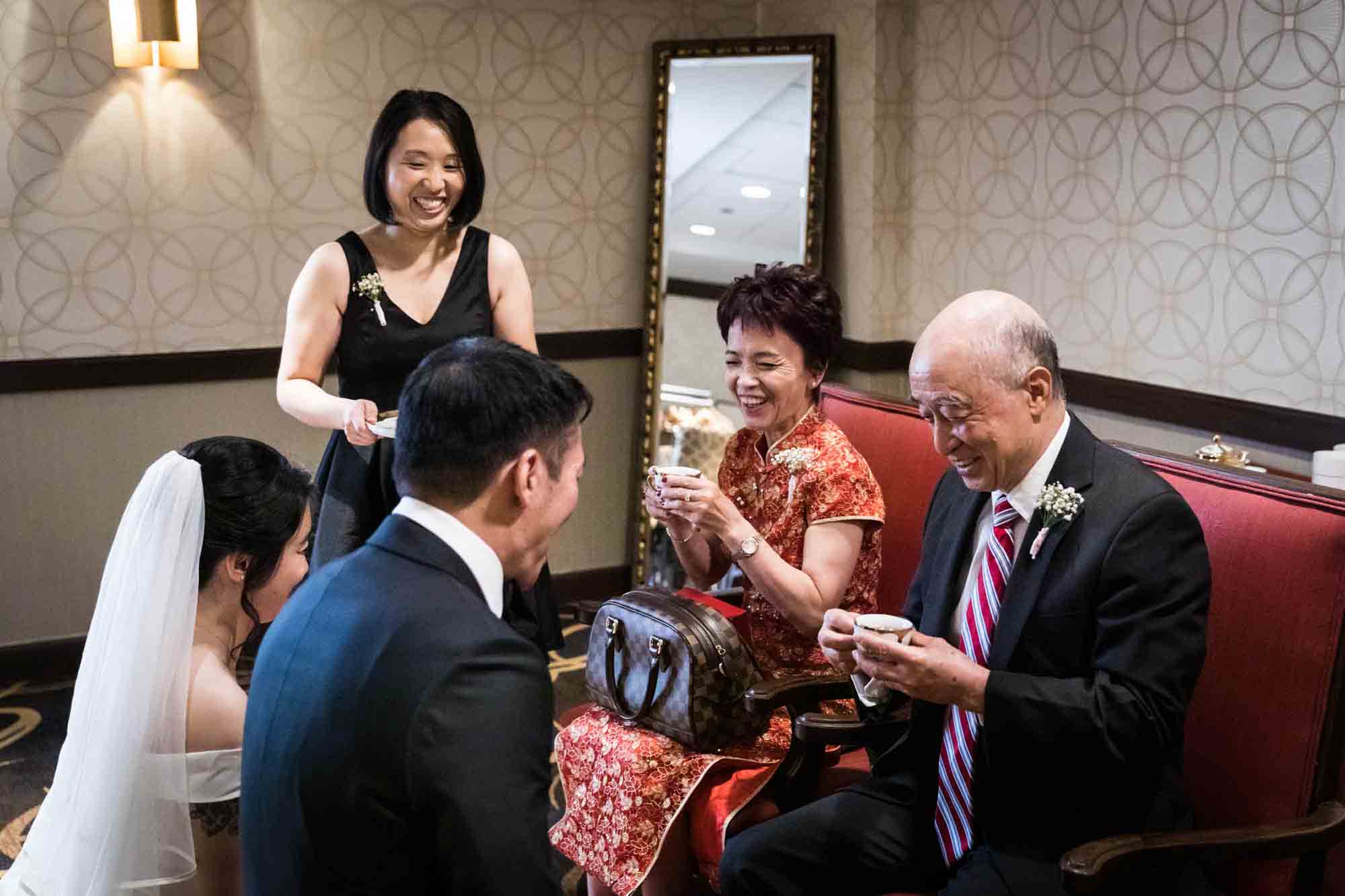 Parents accepting cups of tea from bride and groom at a Sheraton LaGuardia East Hotel wedding