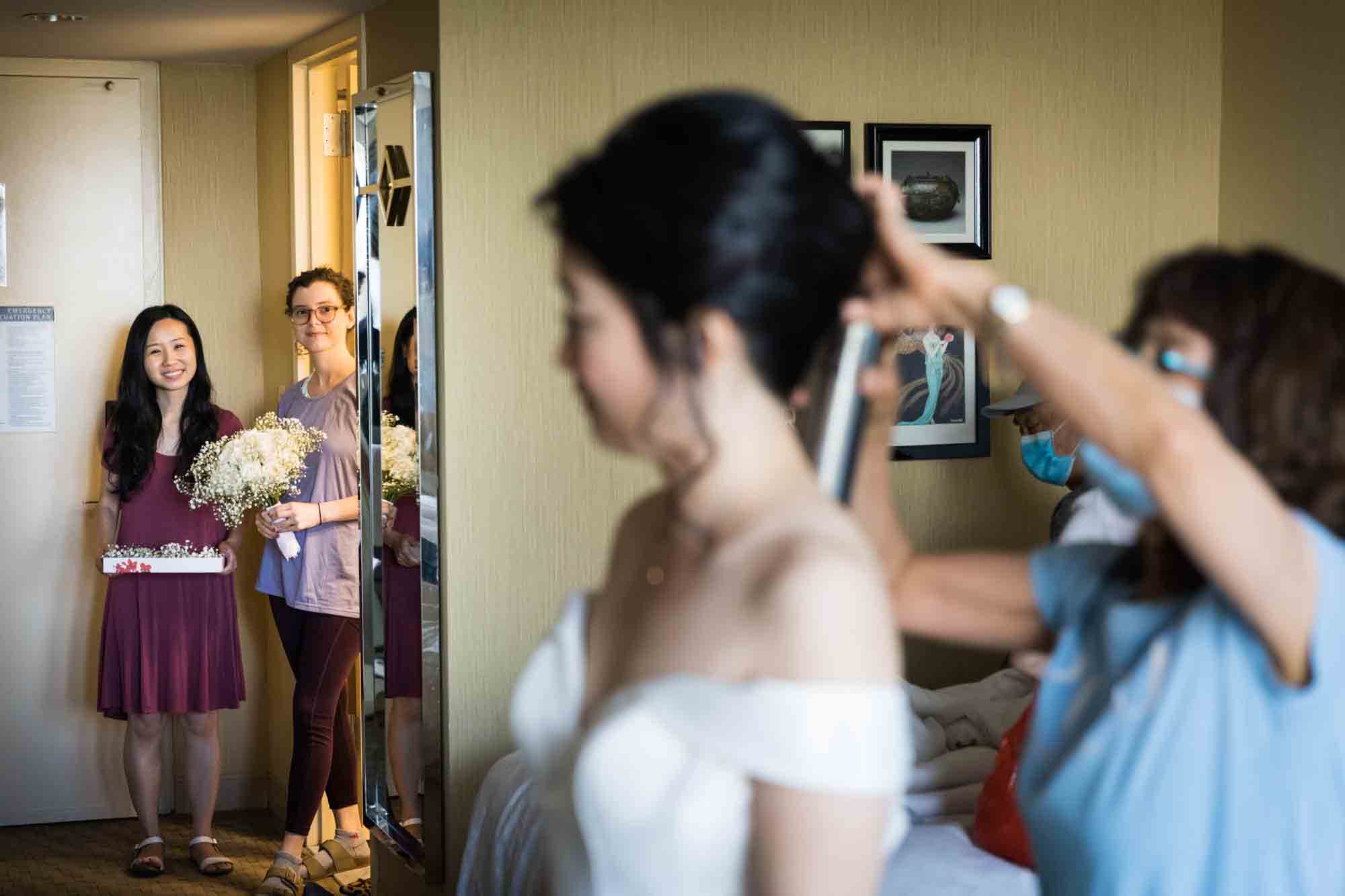 Two women watching veil being put into bride's hair at a Sheraton LaGuardia East Hotel wedding