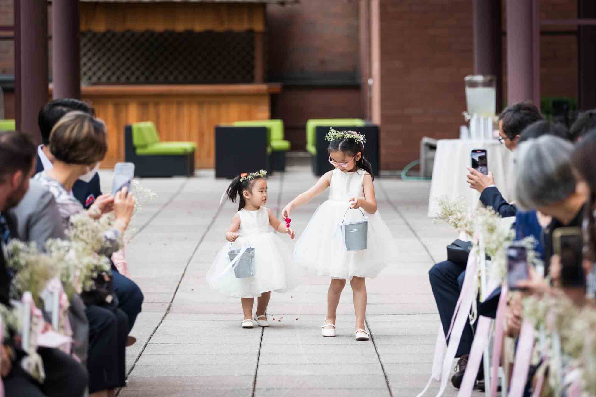 Two little flower girls holding hands and walking down aisle at a Sheraton LaGuardia East Hotel wedding