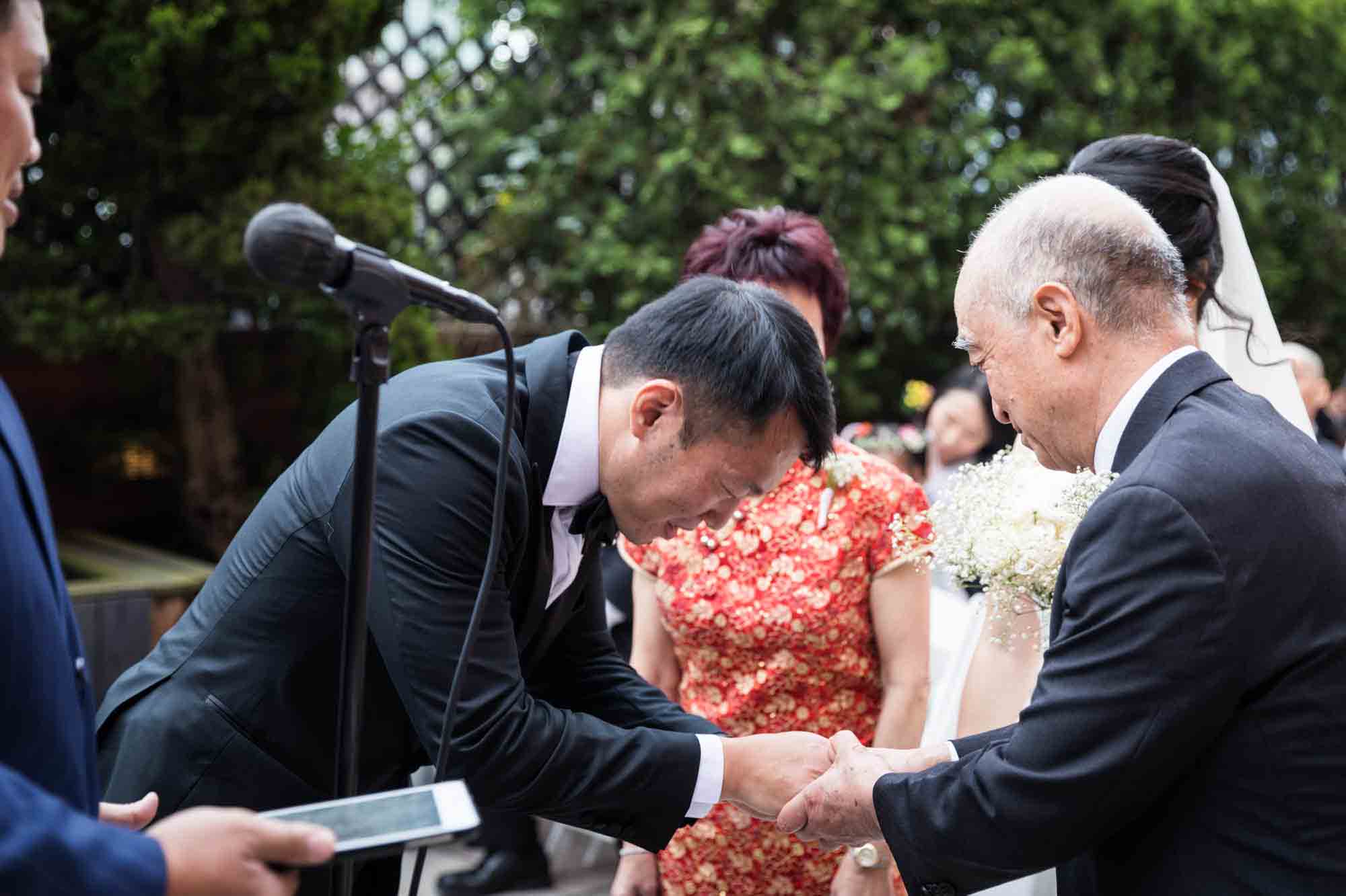 Groom bowing and shaking hand of bride's father during ceremony at a Sheraton LaGuardia East Hotel wedding