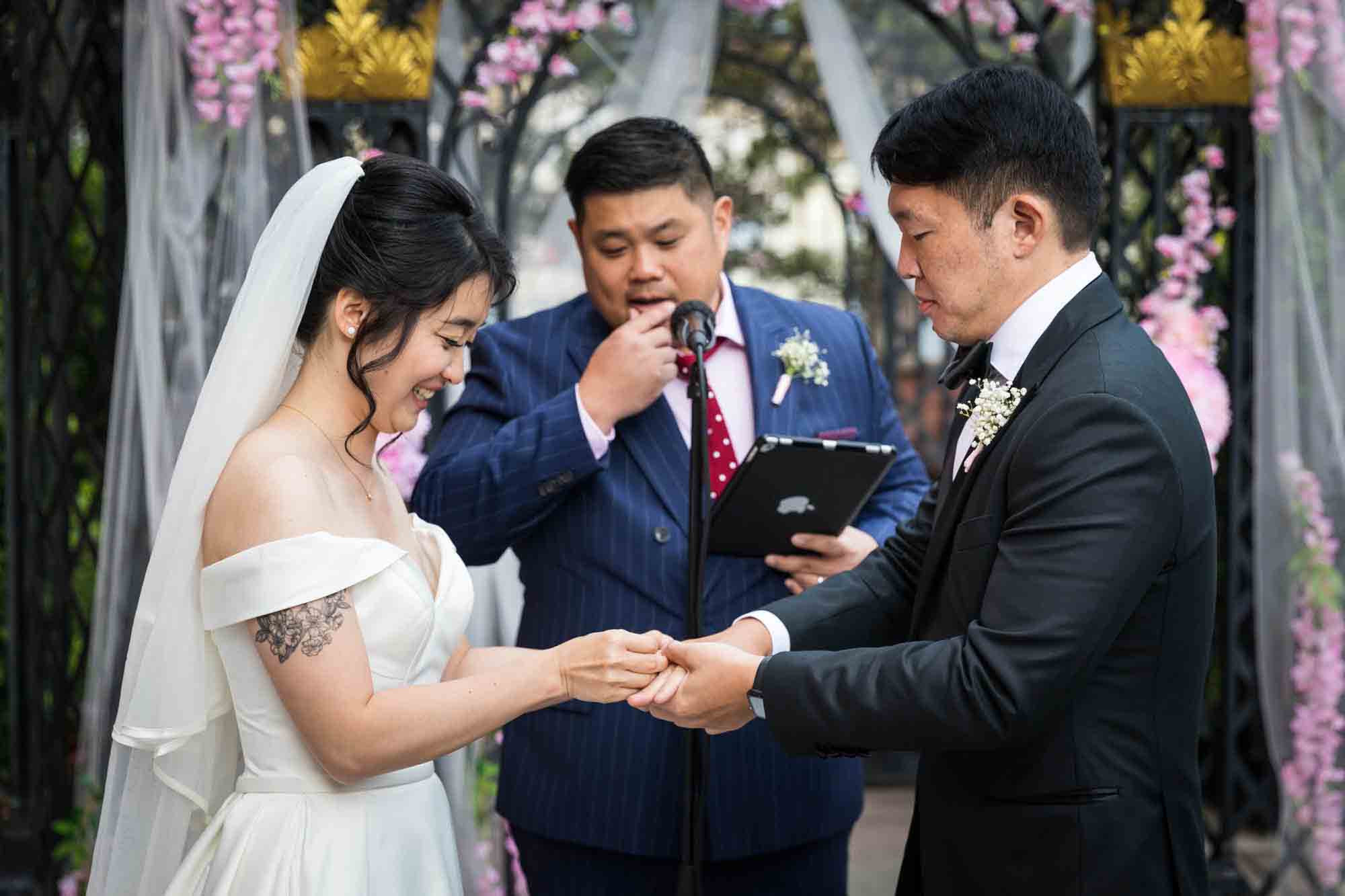 Groom putting ring on bride's finger during ceremony at a Sheraton LaGuardia East Hotel wedding