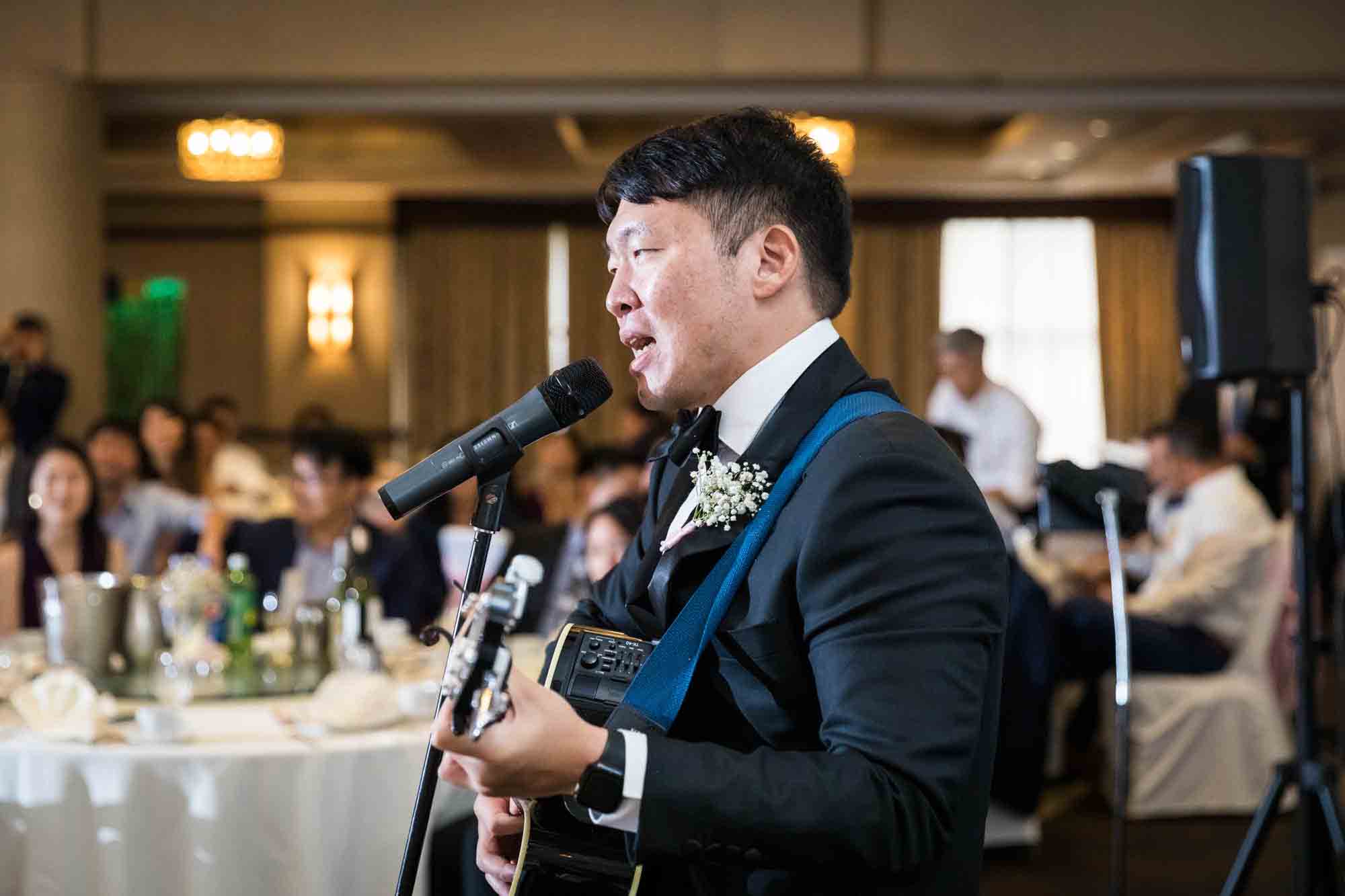 Groom strumming guitar and singing into microphone at a Sheraton LaGuardia East Hotel wedding