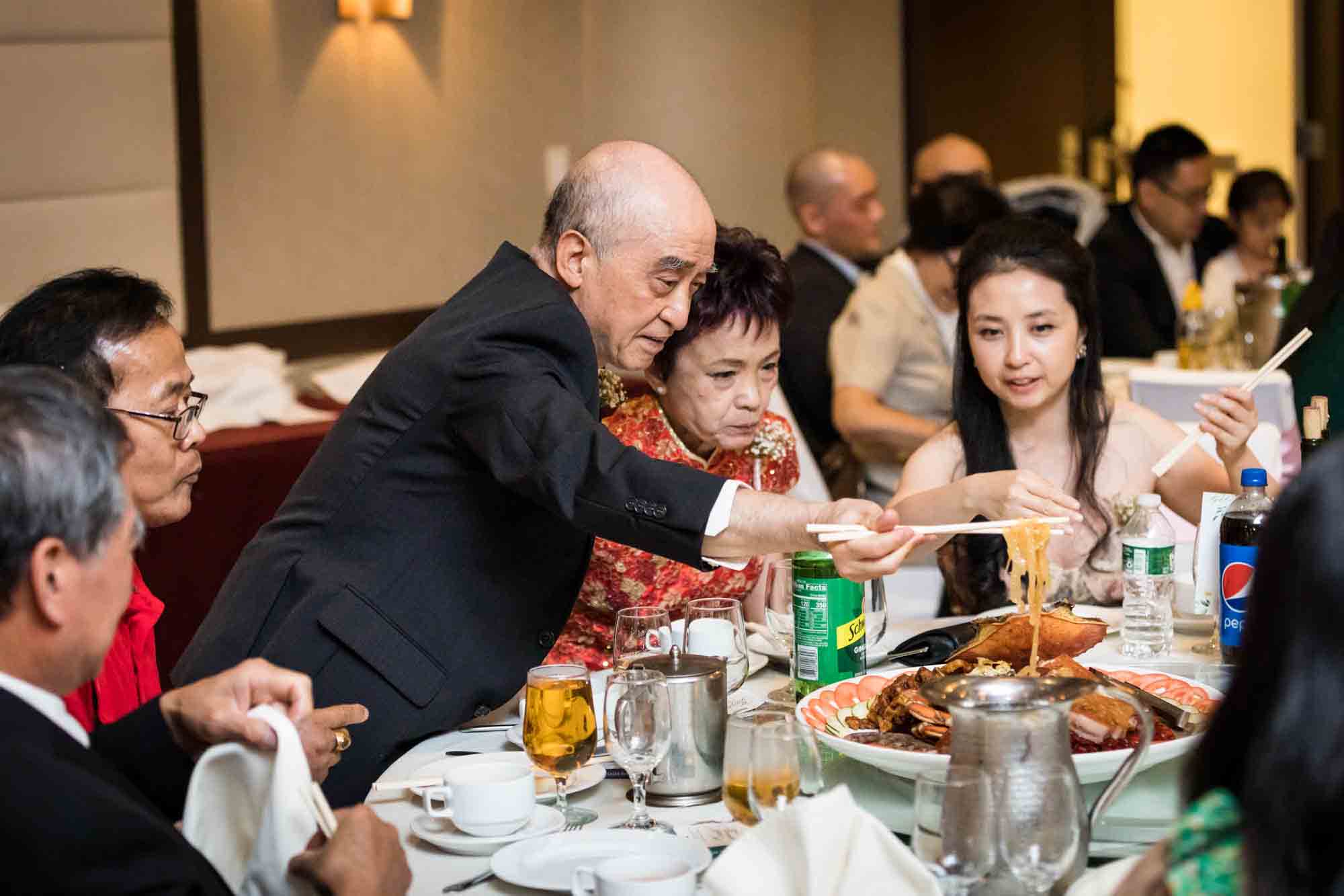 Man lifting up noodles with chopsticks in front of guests at a Sheraton LaGuardia East Hotel wedding