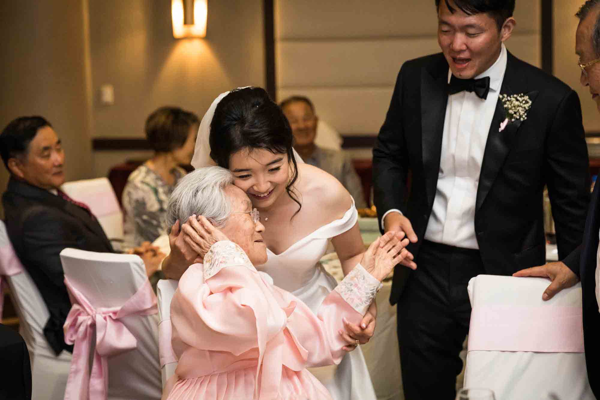 Bride receiving hug from grandmother in front of groom at a Sheraton LaGuardia East Hotel wedding