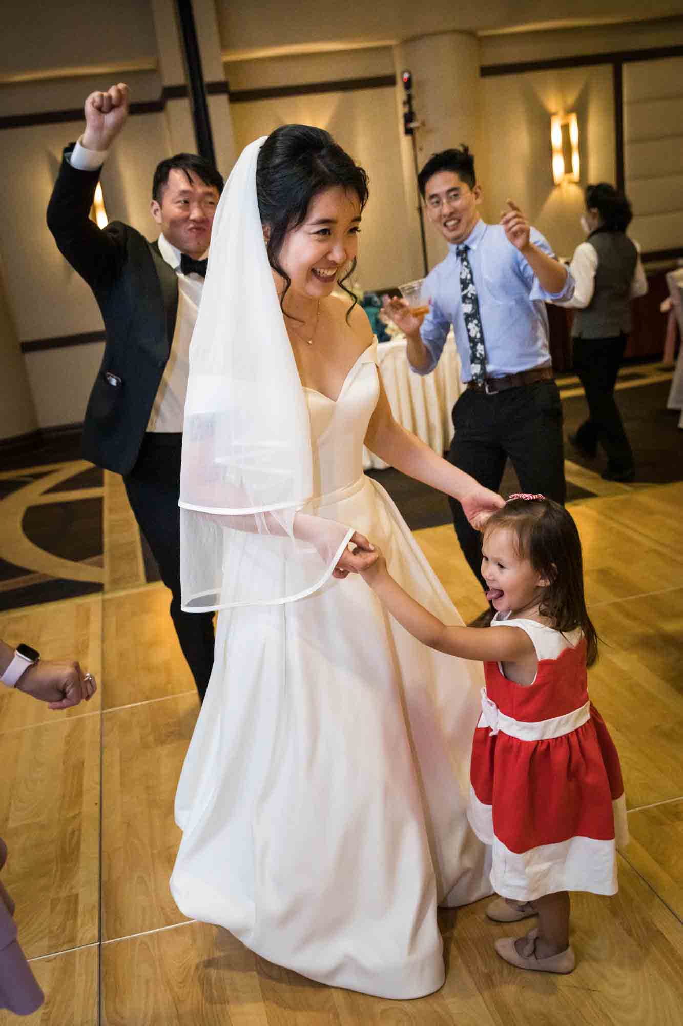 Bride dancing with little girl wearing red dress at a Sheraton LaGuardia East Hotel wedding