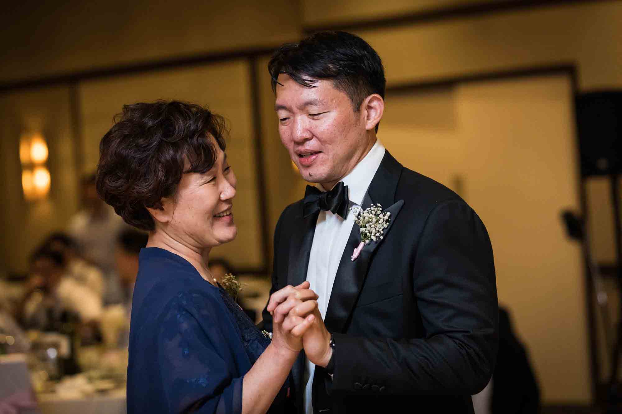 Groom dancing with mother wearing navy dress at a Sheraton LaGuardia East Hotel wedding