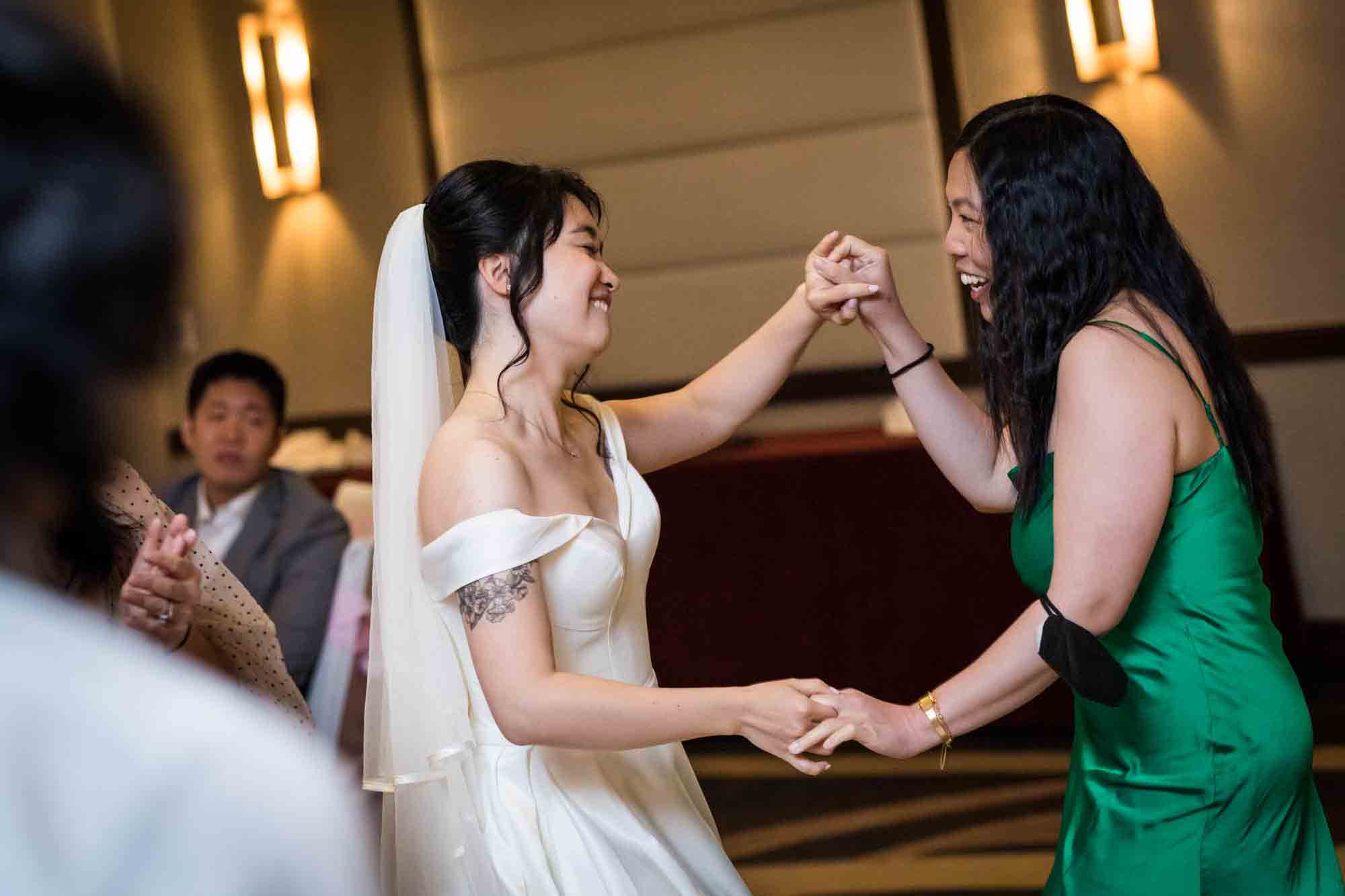 Bride dancing with female guest at a Sheraton LaGuardia East Hotel wedding