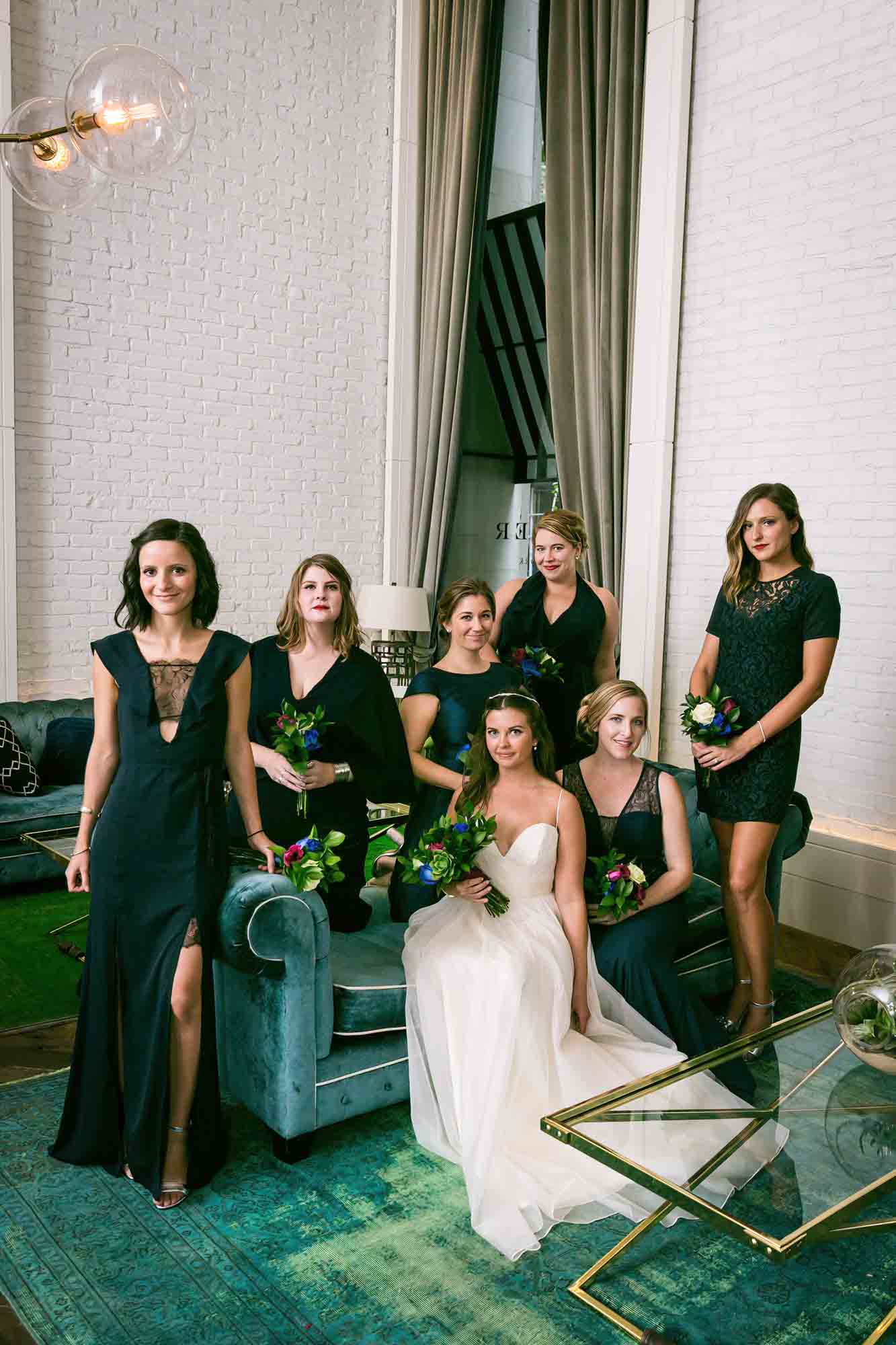 Portrait of bride and bridesmaids sitting on green couch before a Bathhouse Studios wedding