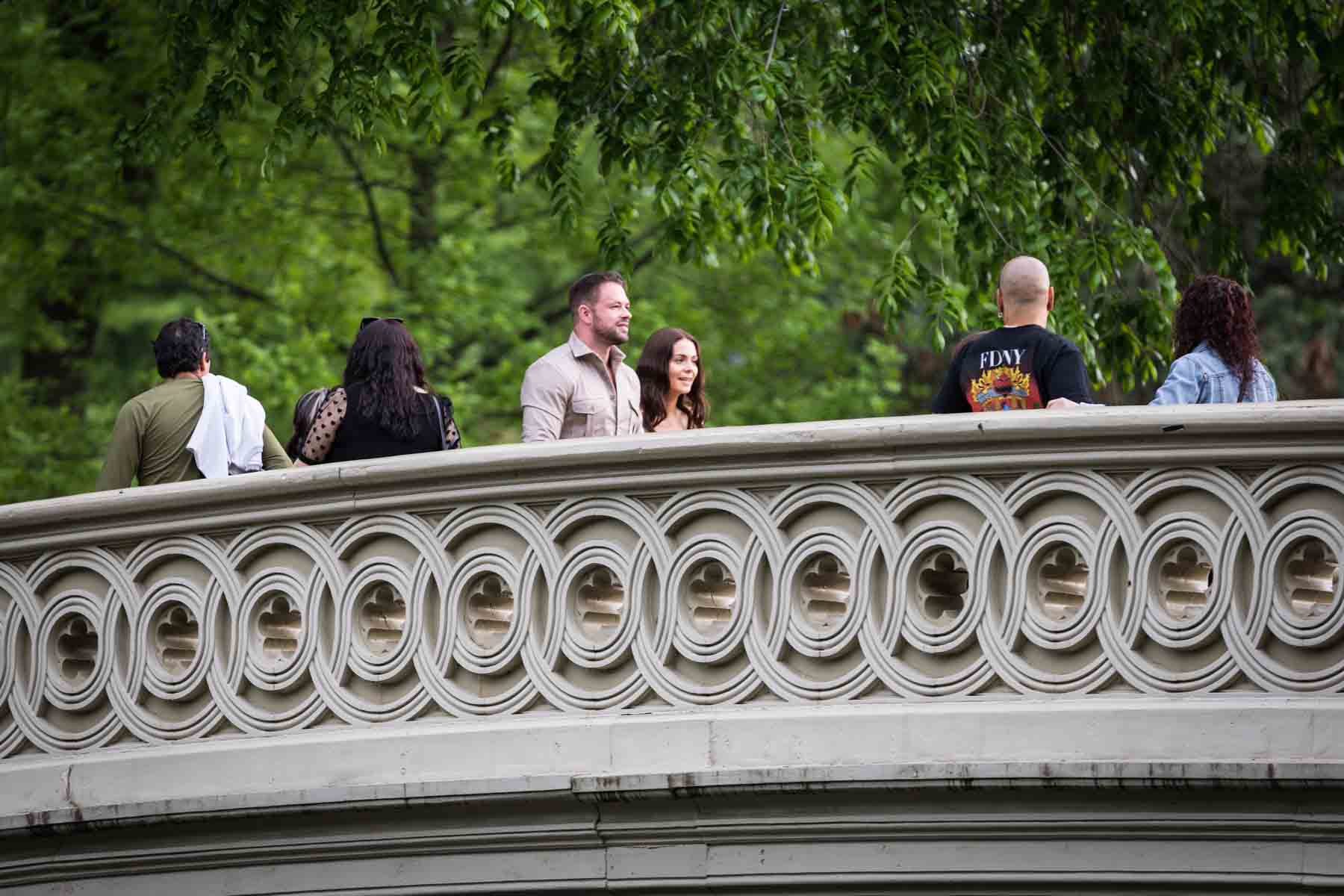 Couple walking over Bow Bridge during a Central Park surprise proposal