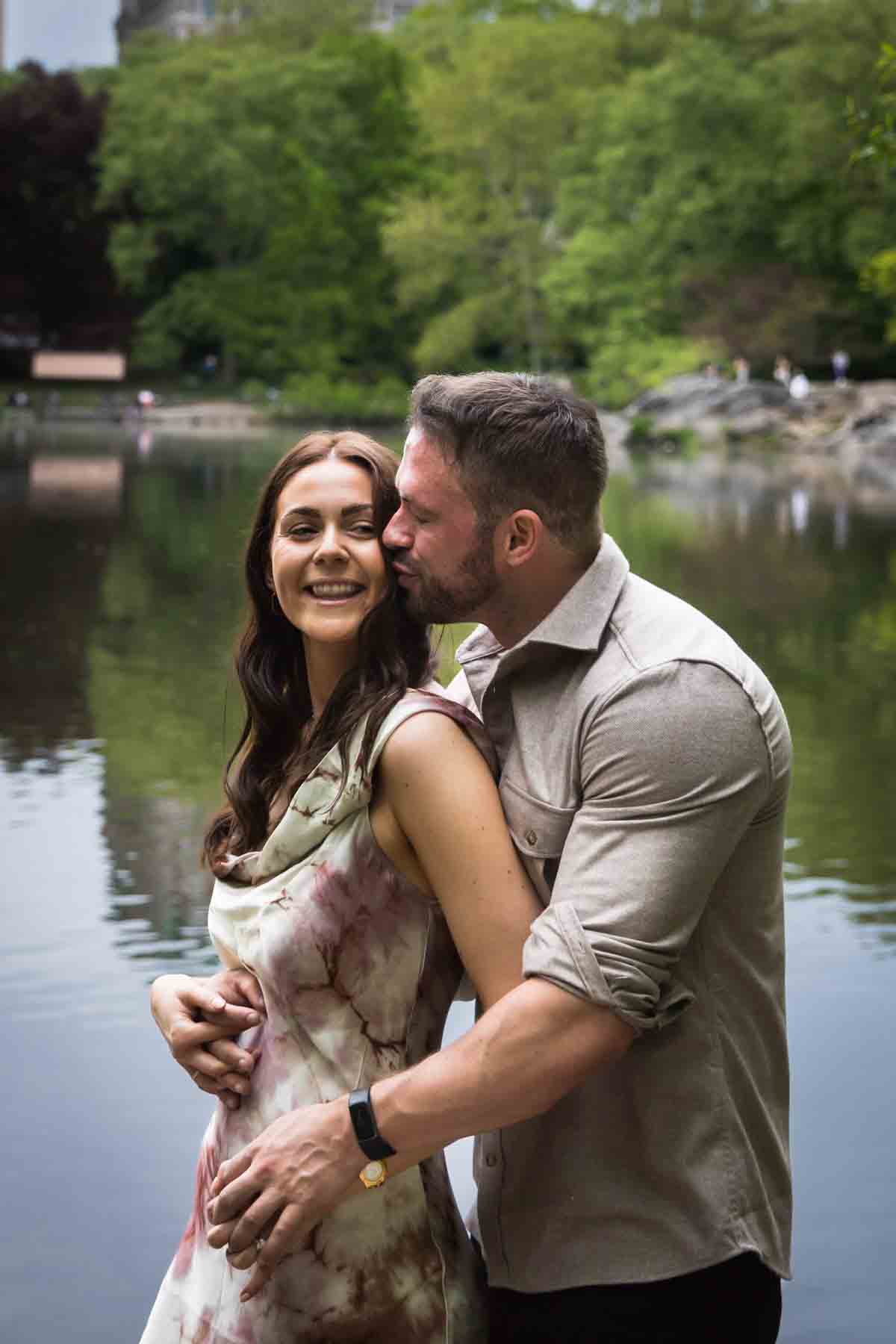 Man kissing woman in front of lake during a Central Park surprise proposal