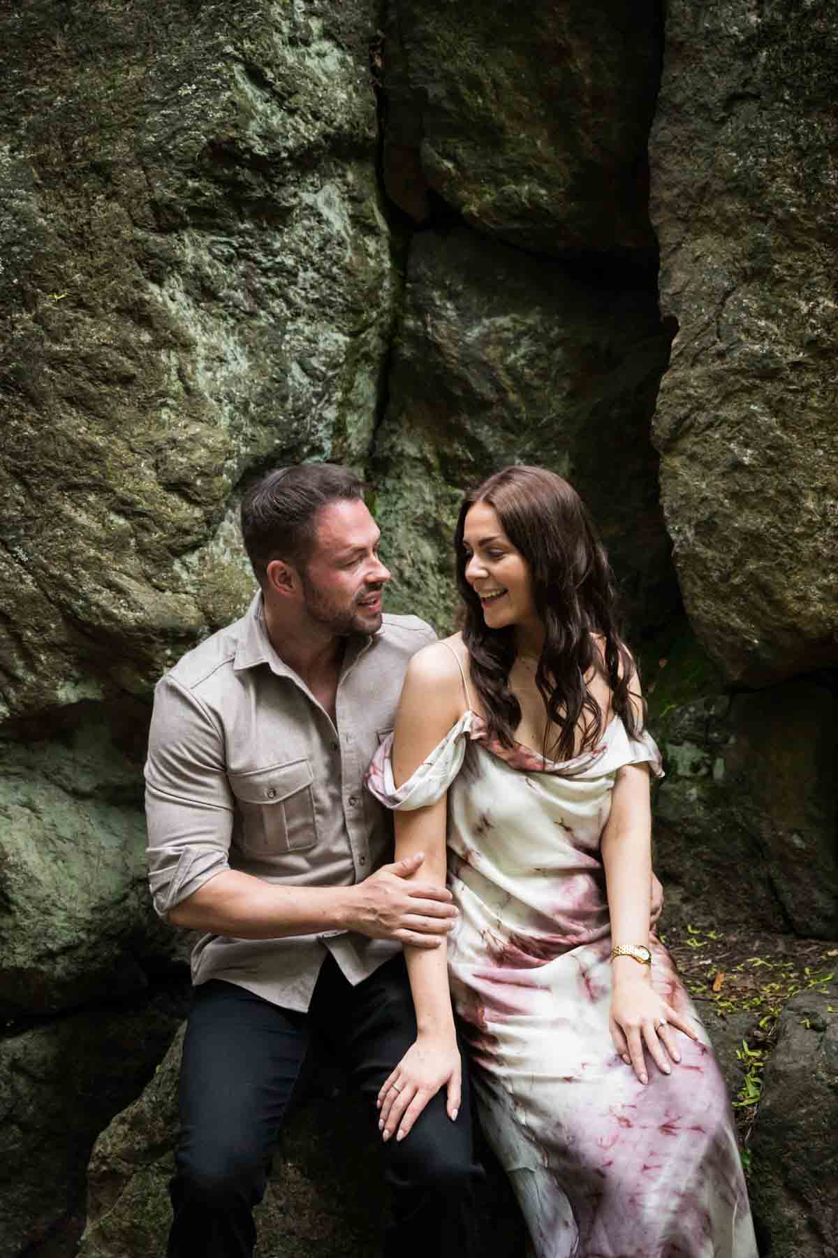 Couple sitting in front of rock walls for an article on the best places to propose in Central Park