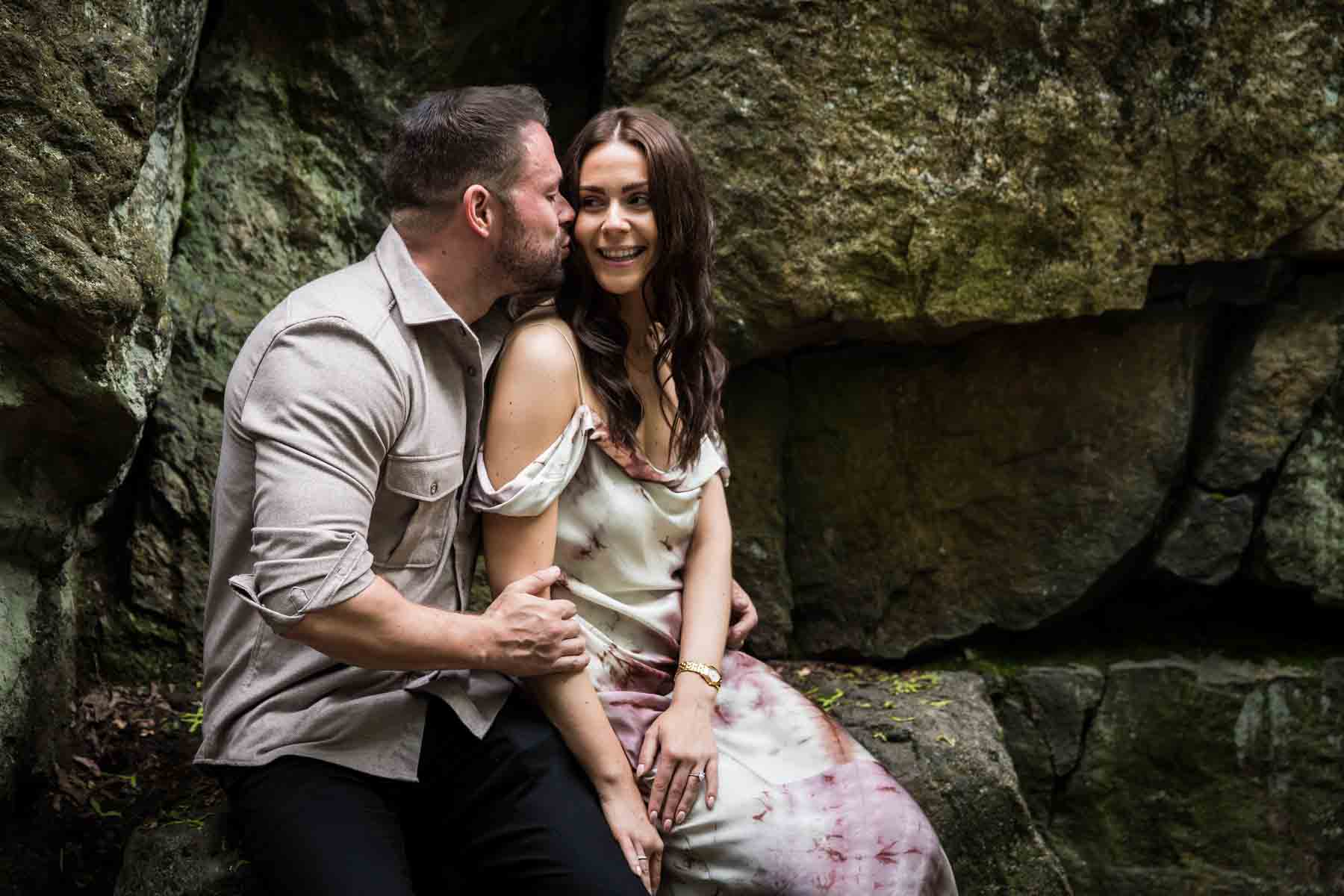 Couple sitting in front of rock walls for an article on the best places to propose in Central Park