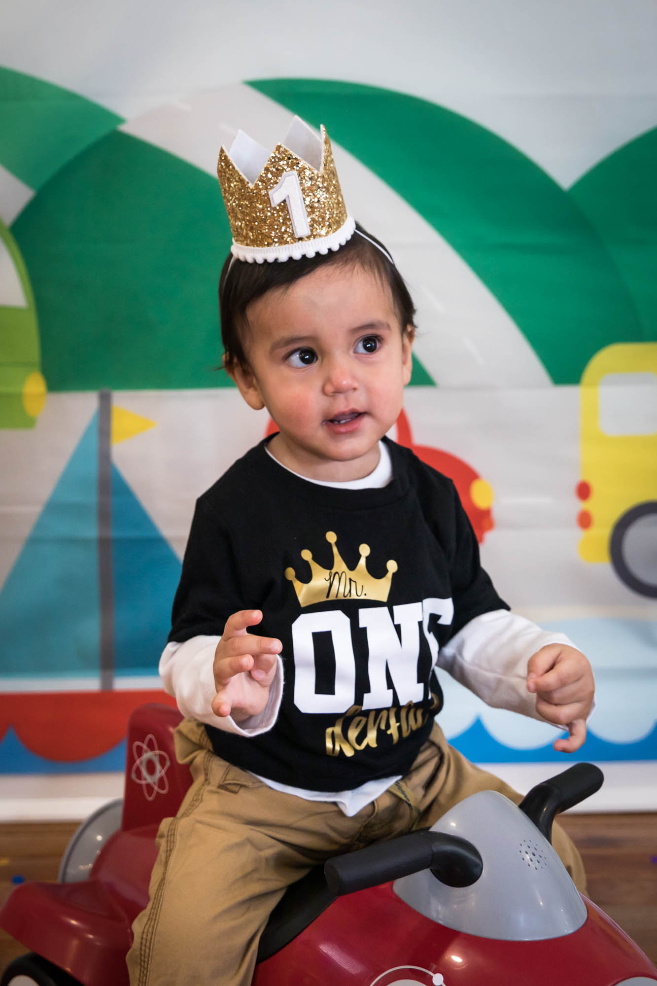 Little boy wearing black t-shirt and gold crown sitting on scooter during a Queens family portrait