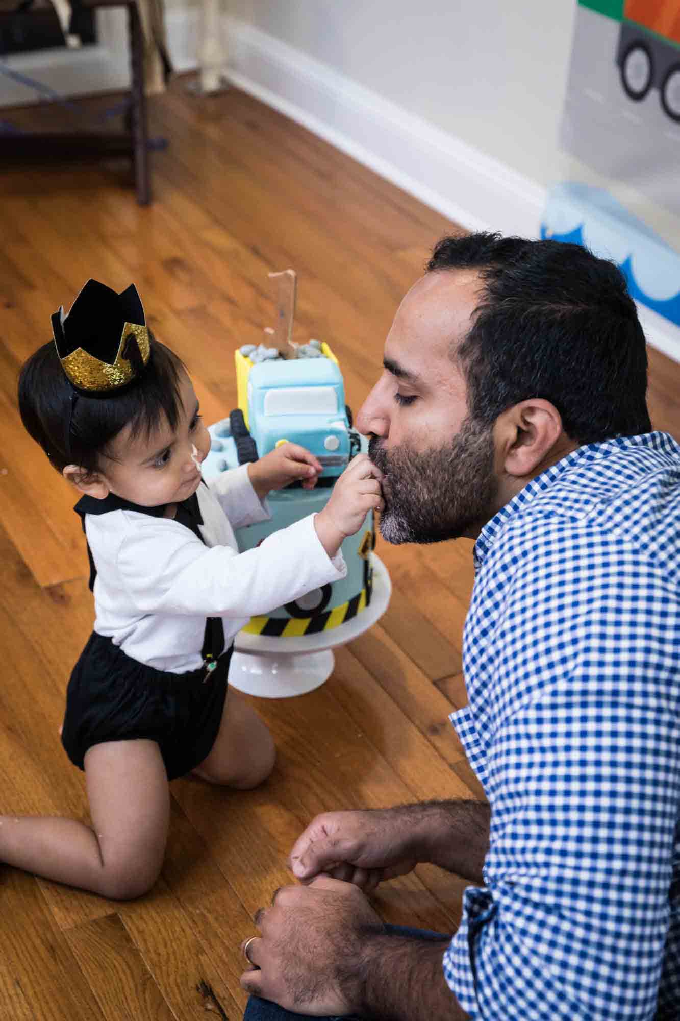 Little boy feeding cake to father on a wooden floor for an article on cake smash tips