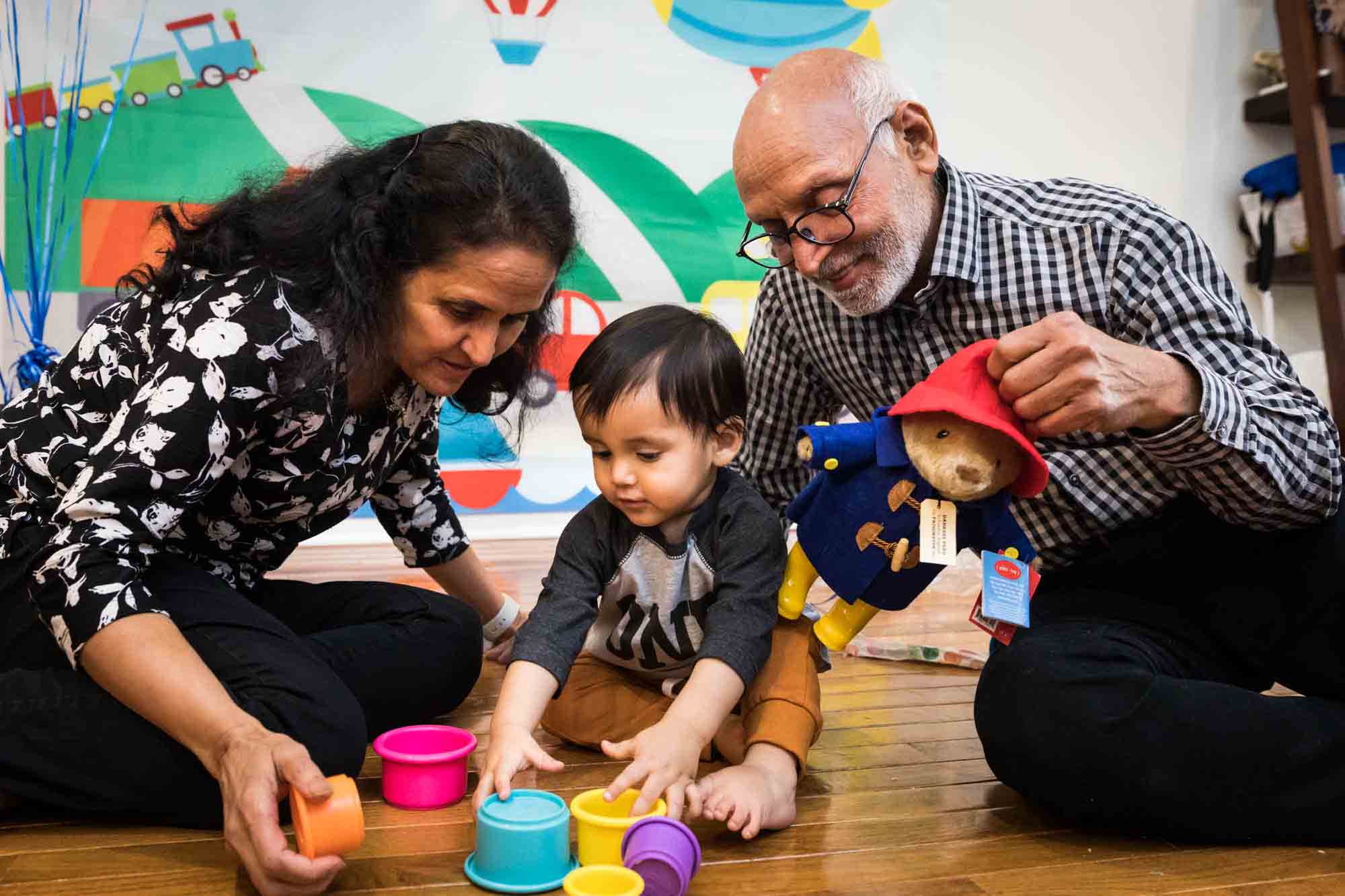 Grandparents playing with little boy on a wooden floor for an article on cake smash tips