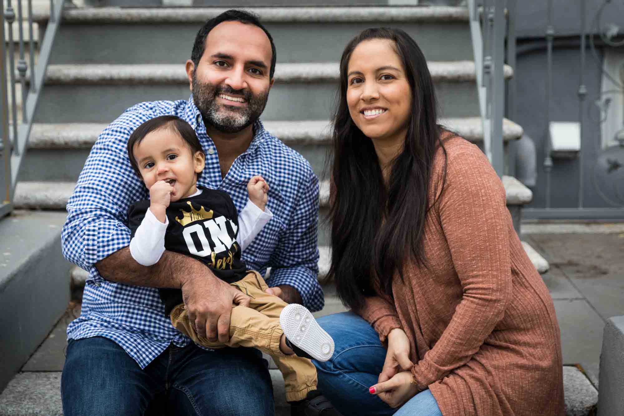 Mother and father holding little boy on steps in front of NYC apartment for a Queens family portrait