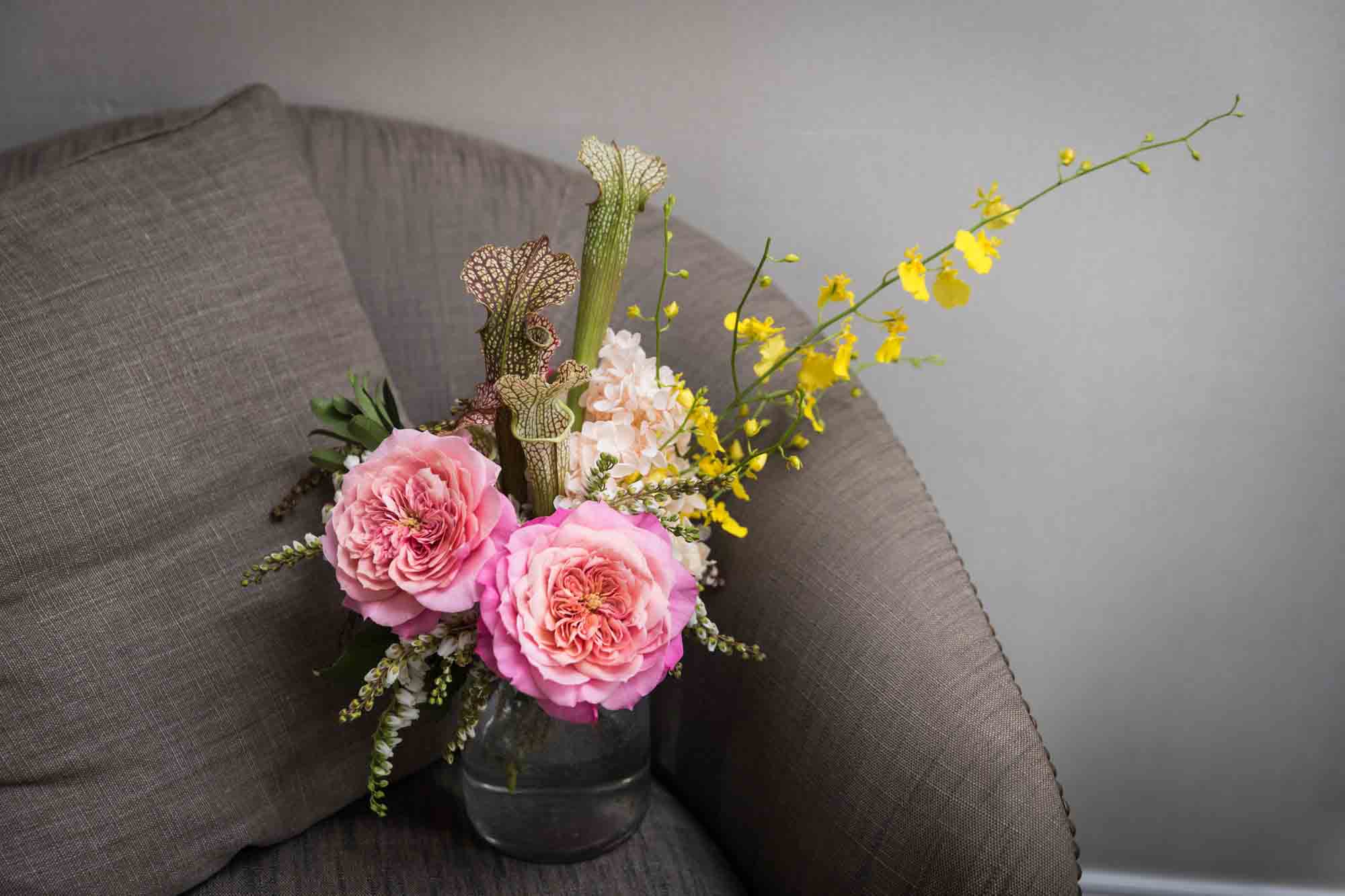 Colorful flower bouquet with two pink roses and spray of yellow flowers on beige chair
