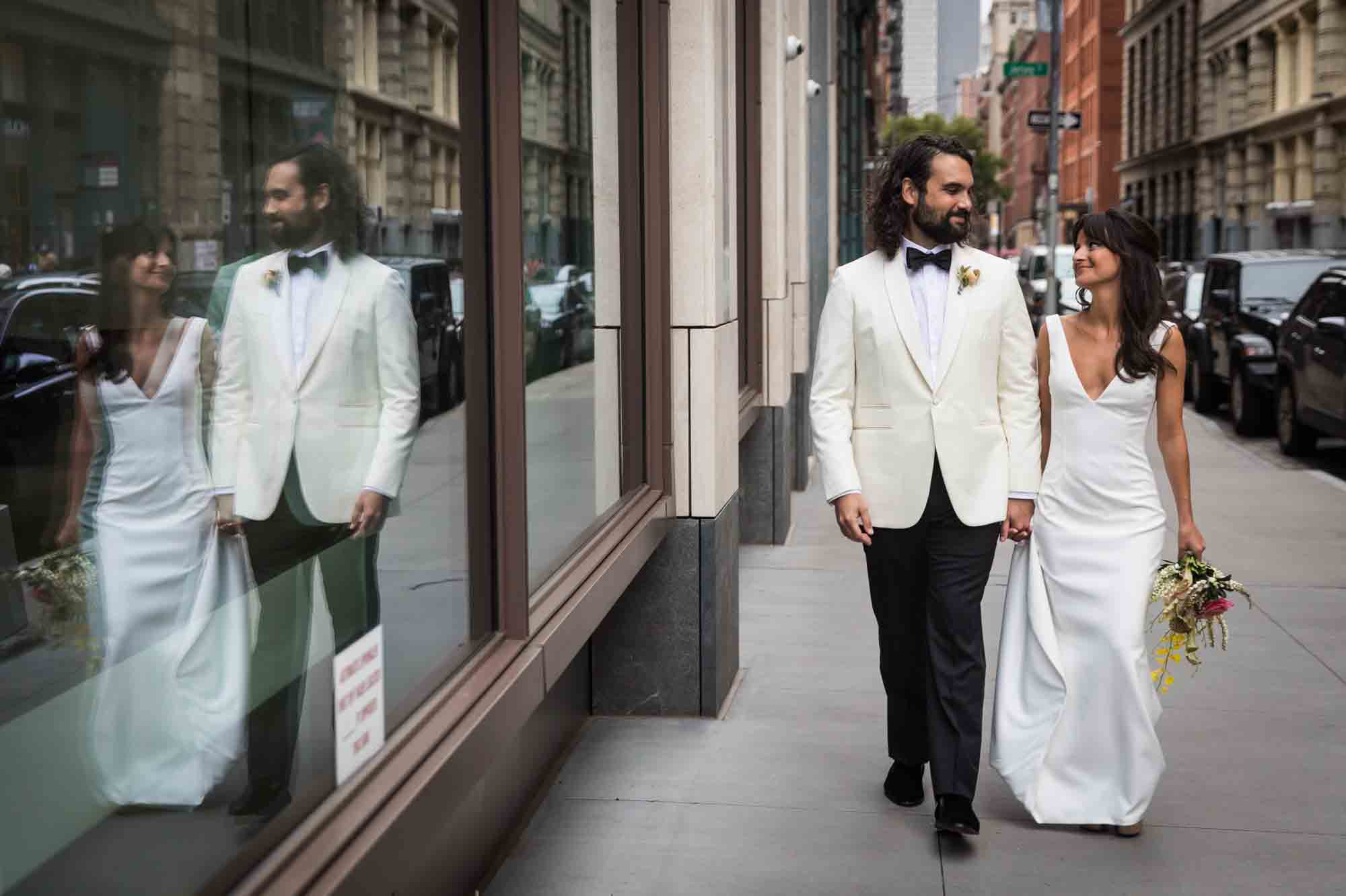 Bride and groom walking past window on sidewalk with reflection