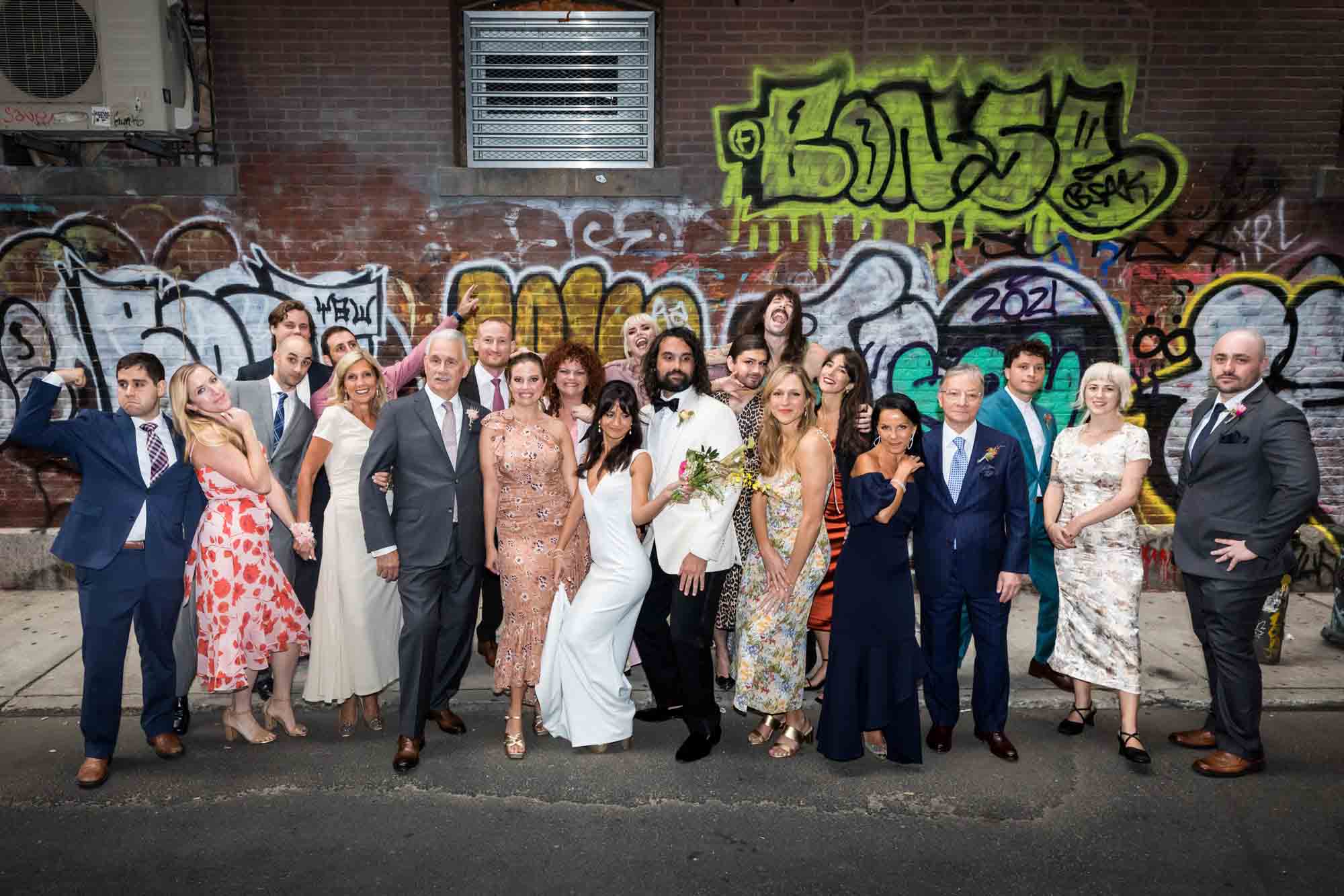 Group photo of family and friends making funny faces in front of graffiti at a Housing Works wedding