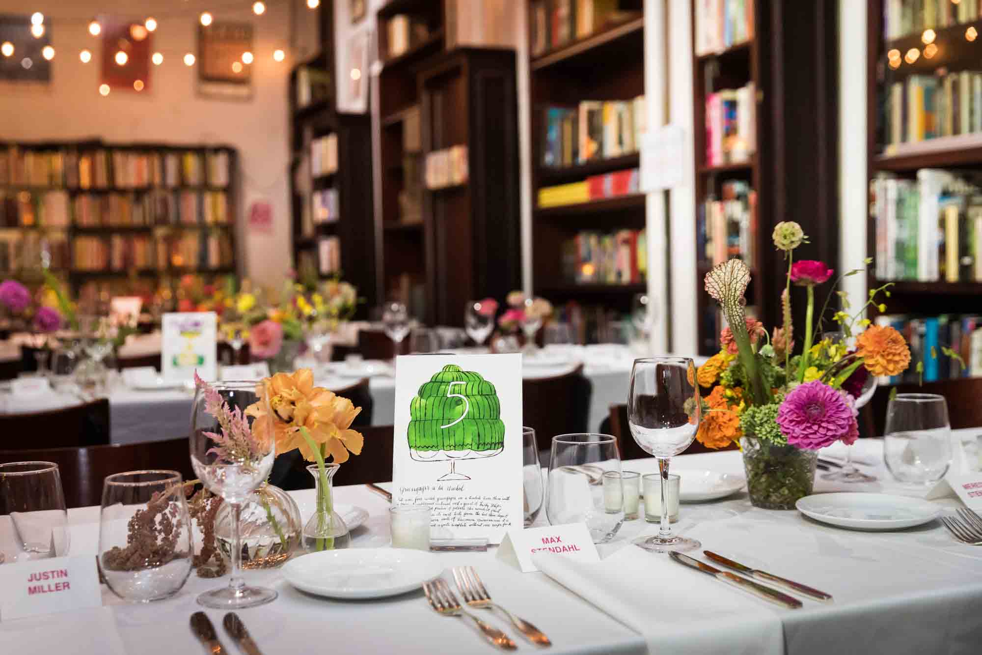 Tables set with colorful floral arrangements and handmade table numbers at a Housing Works wedding