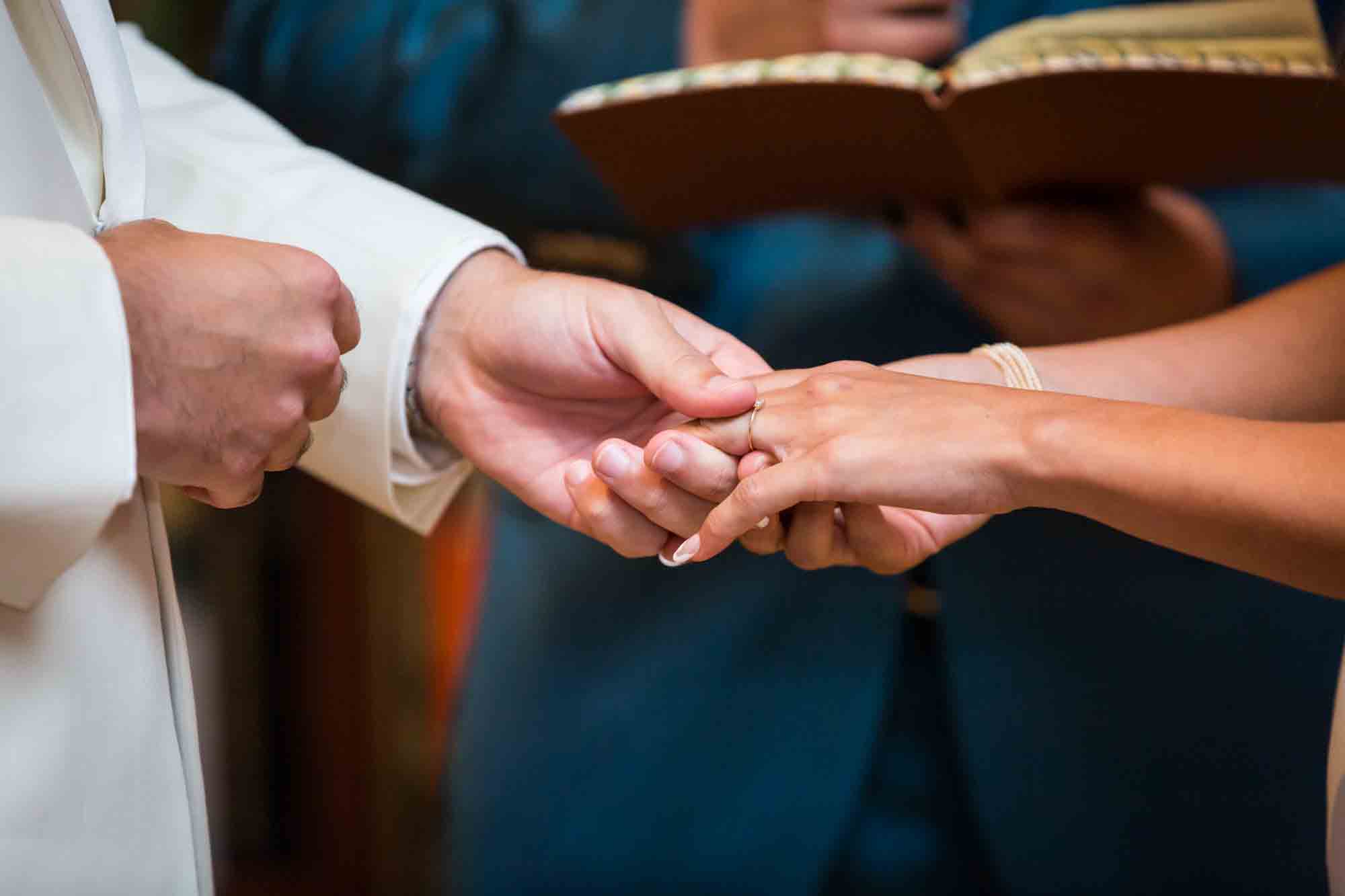 Close up of groom putting wedding ring on bride's hand