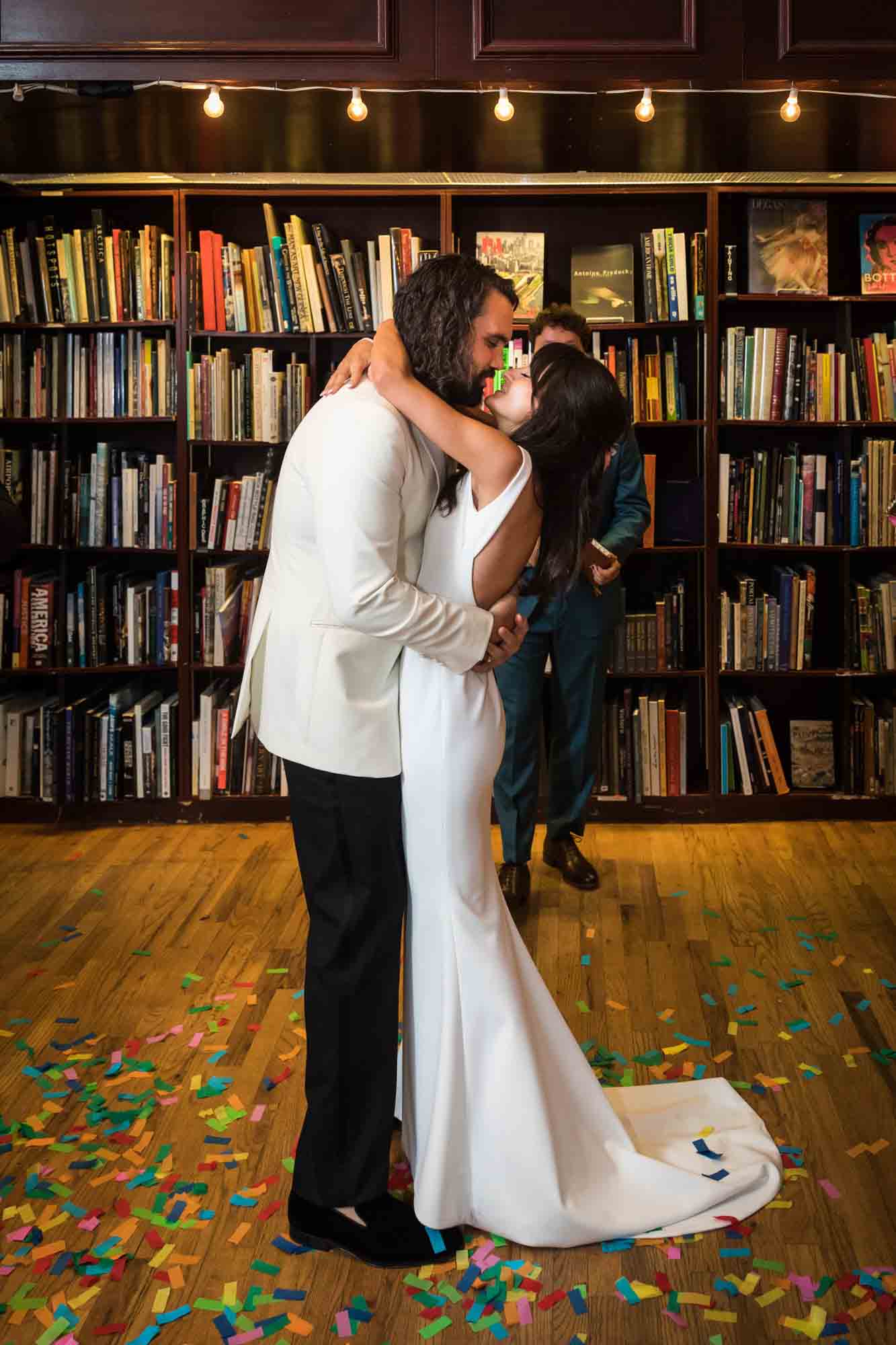 Bride and groom hugging with confetti on wood floor at a Housing Works wedding