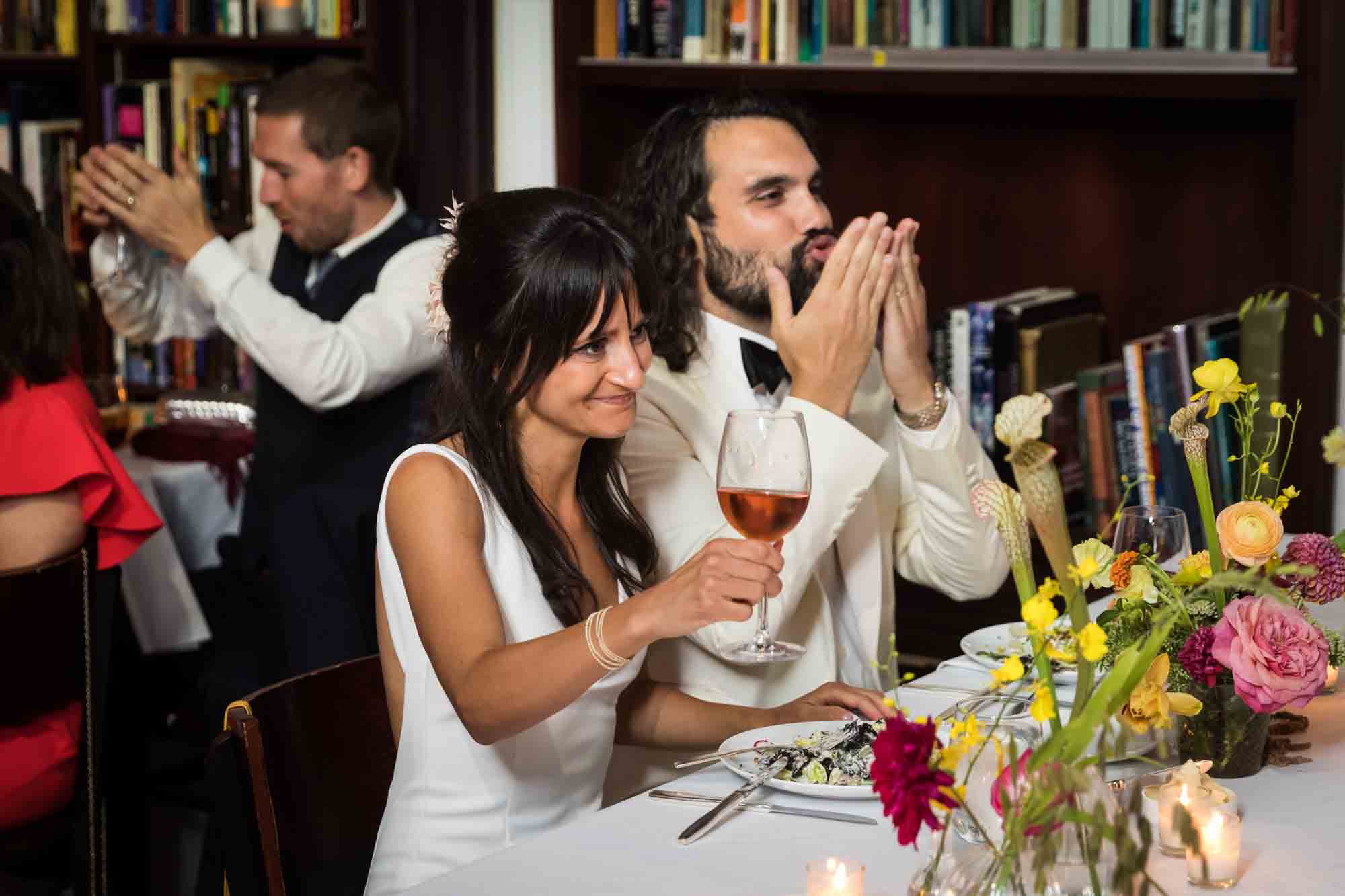 Bride lifting wine glass next to groom at table during a Housing Works wedding