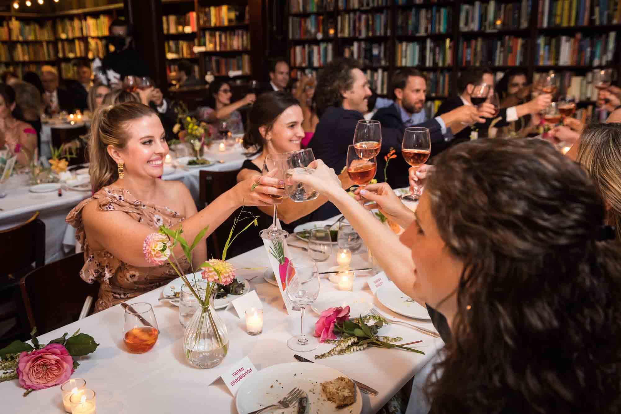 Guests cheering wine glasses at tables during a Housing Works wedding