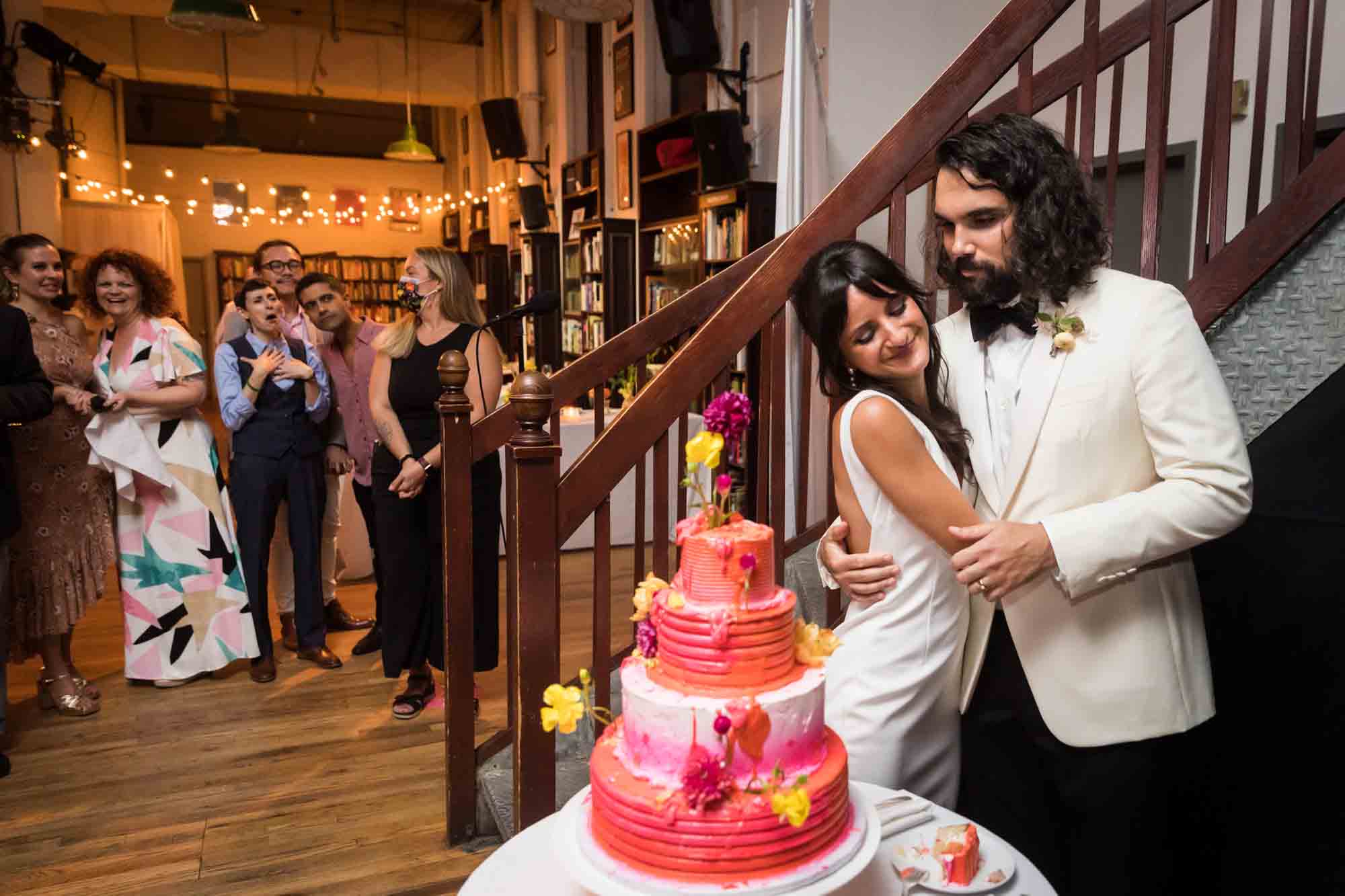 Bride and groom hugging behind neon yellow wedding cake at a Housing Works wedding