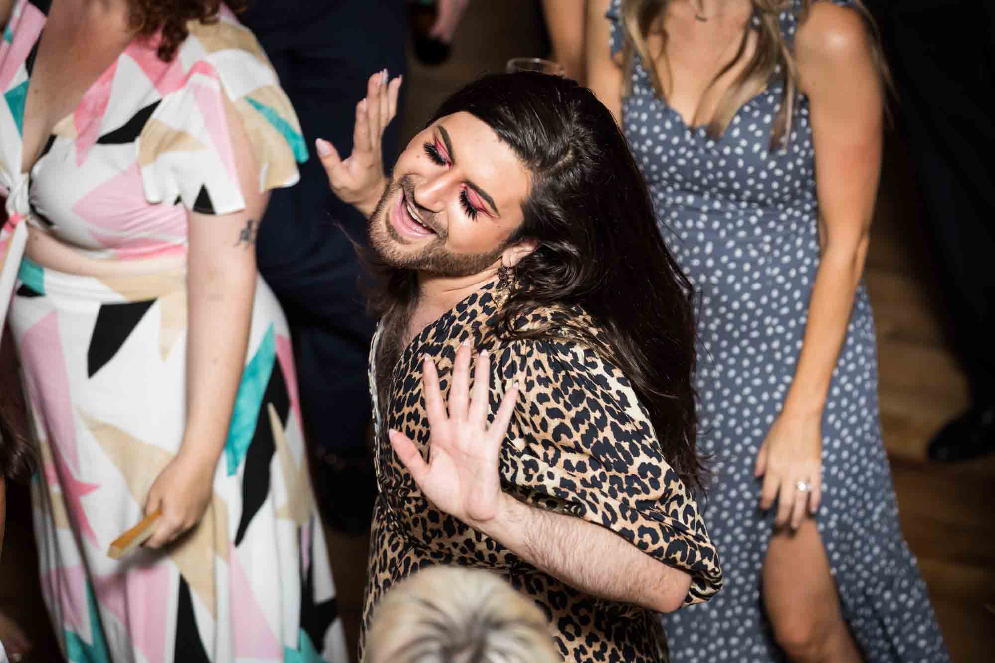 Man wearing eye shadow and a leopard dress dancing at a Housing Works wedding