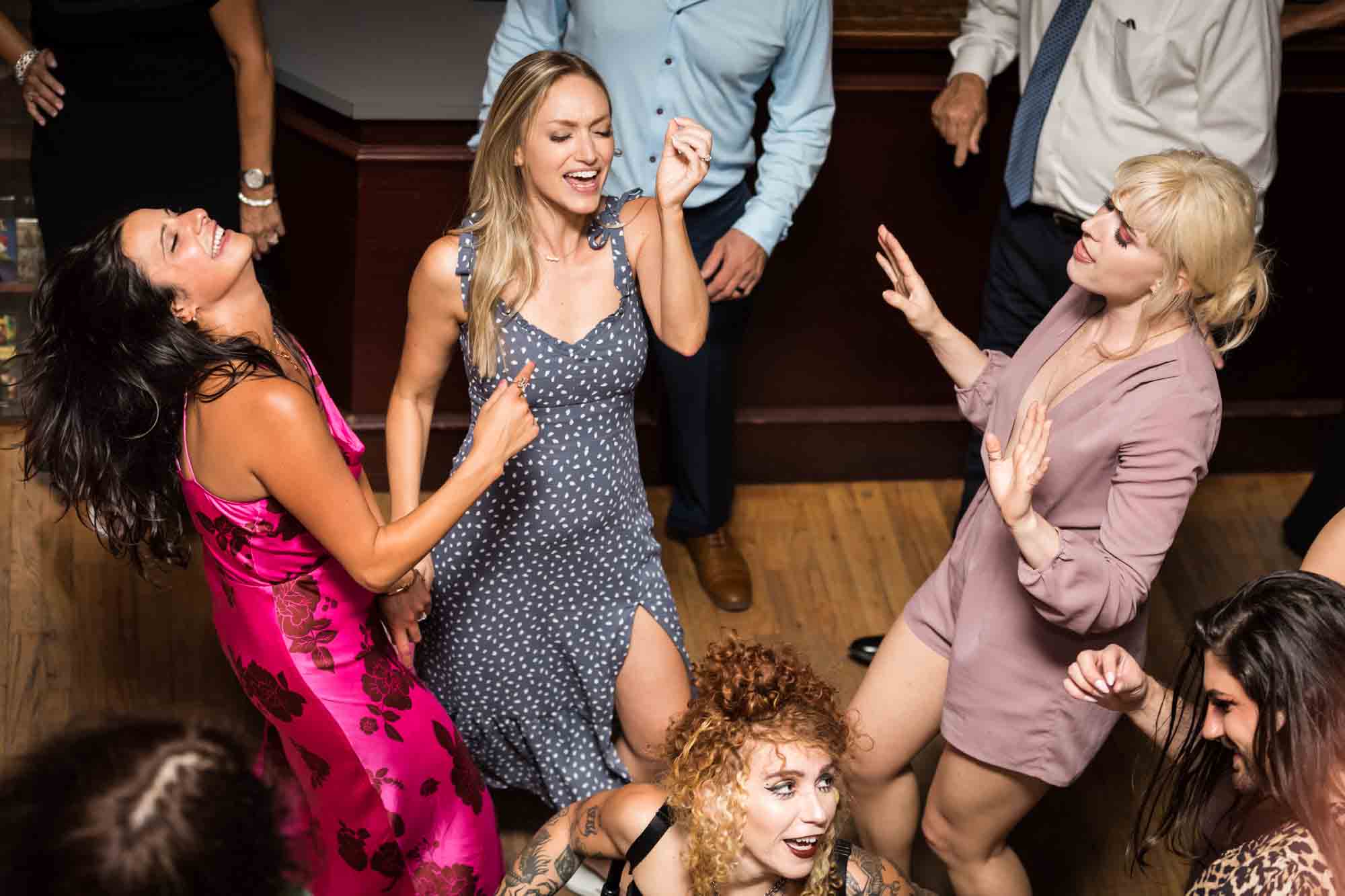 Three women dancing with arms up at a Housing Works wedding