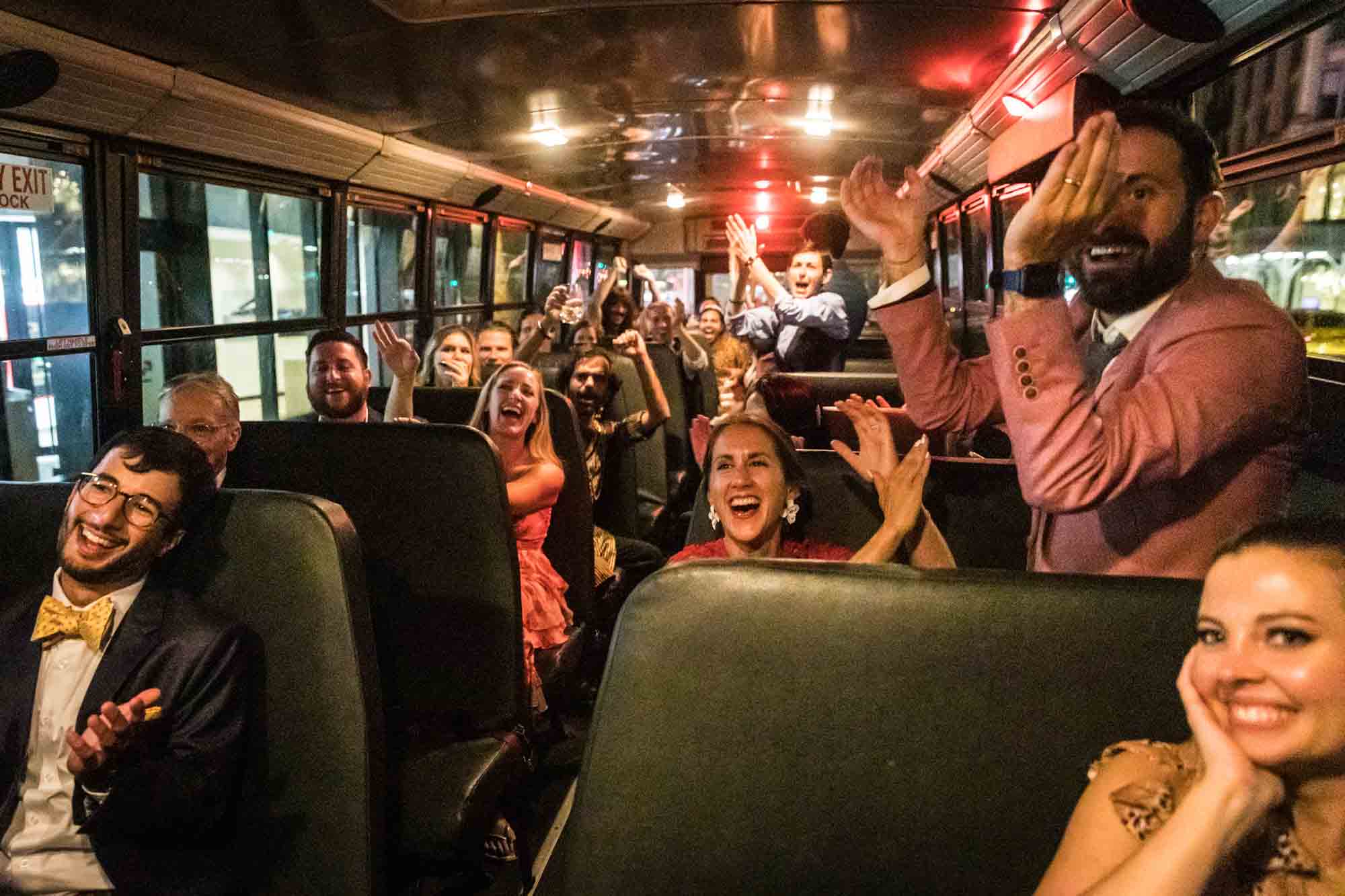 Guests on school bus clapping for bride and groom
