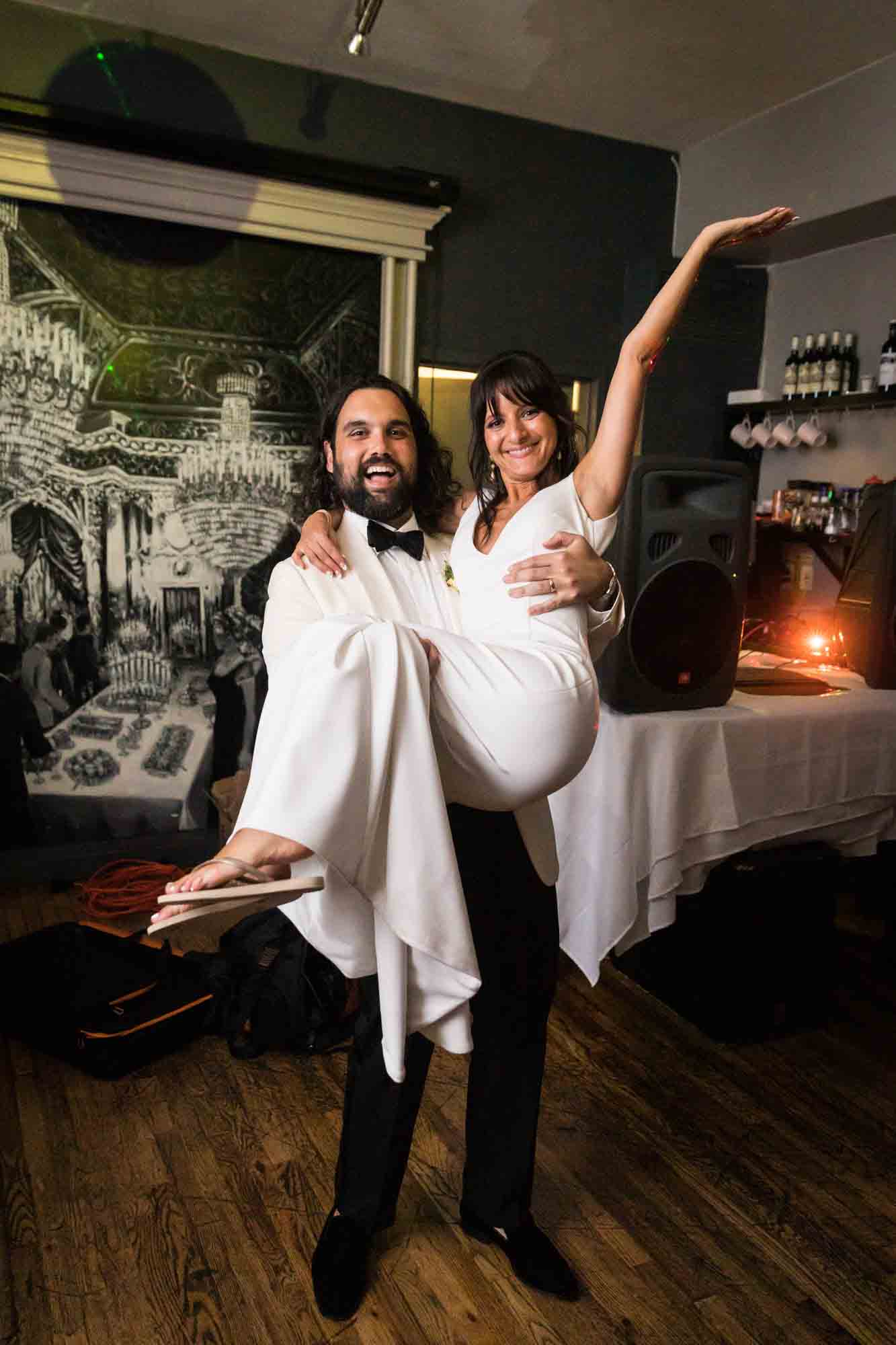 Groom holding bride with arm up in middle of bar